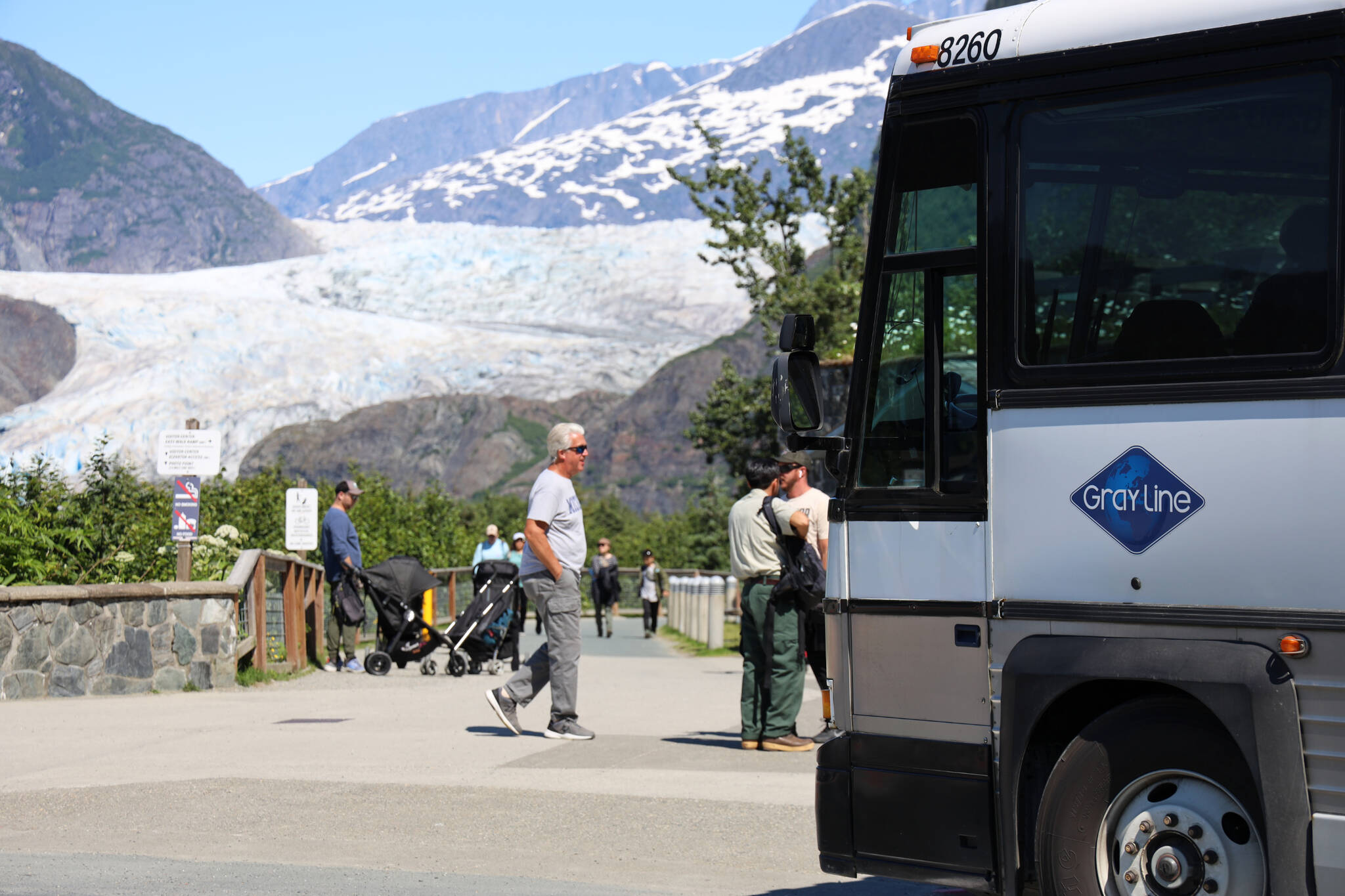 A bus picks up visitors at the Mendenhall Glacier Visitor Center Friday morning. Local tourism companies are being forced to turn away tourists in Juneau seeking to visit the area this summer as commercial tourism limits are being reached rapidly. (Clarise Larson / Juneau Empire)