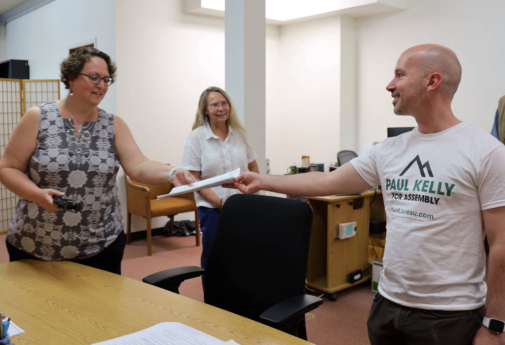 City and Borough of Juneau resident Paul Kelly hands his candidacy forms to City Clerk Beth McEwen within minutes of the local election filing period opening on Friday. Kelly is running for one of the two areawide seats open on the Assembly. (Clarise Larson / Juneau Empire)