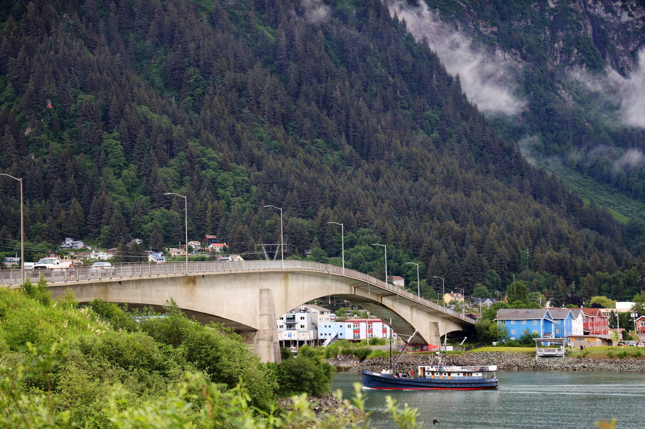 A boat passes under the Juneau-Douglas Bridge in late June. A person reportedly jumped off the bridge managed to make it to Overstreet Park on Saturday evening, according to the Juneau Police Department. (Clarise Larson / Juneau Empire File)