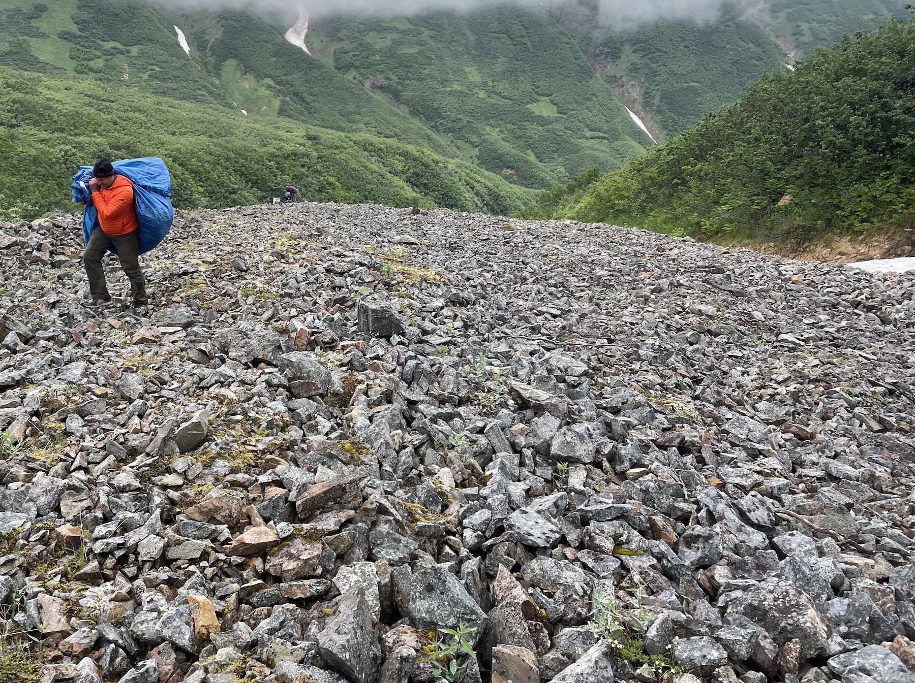Adam Bucki hauls a load of trash from Fireweed rock glacier to the site where a helicopter will pick it up and haul it back to nearby McCarthy. He would later dispose of the trash in a sanitary landfill. (Photo by Ned Rozell)