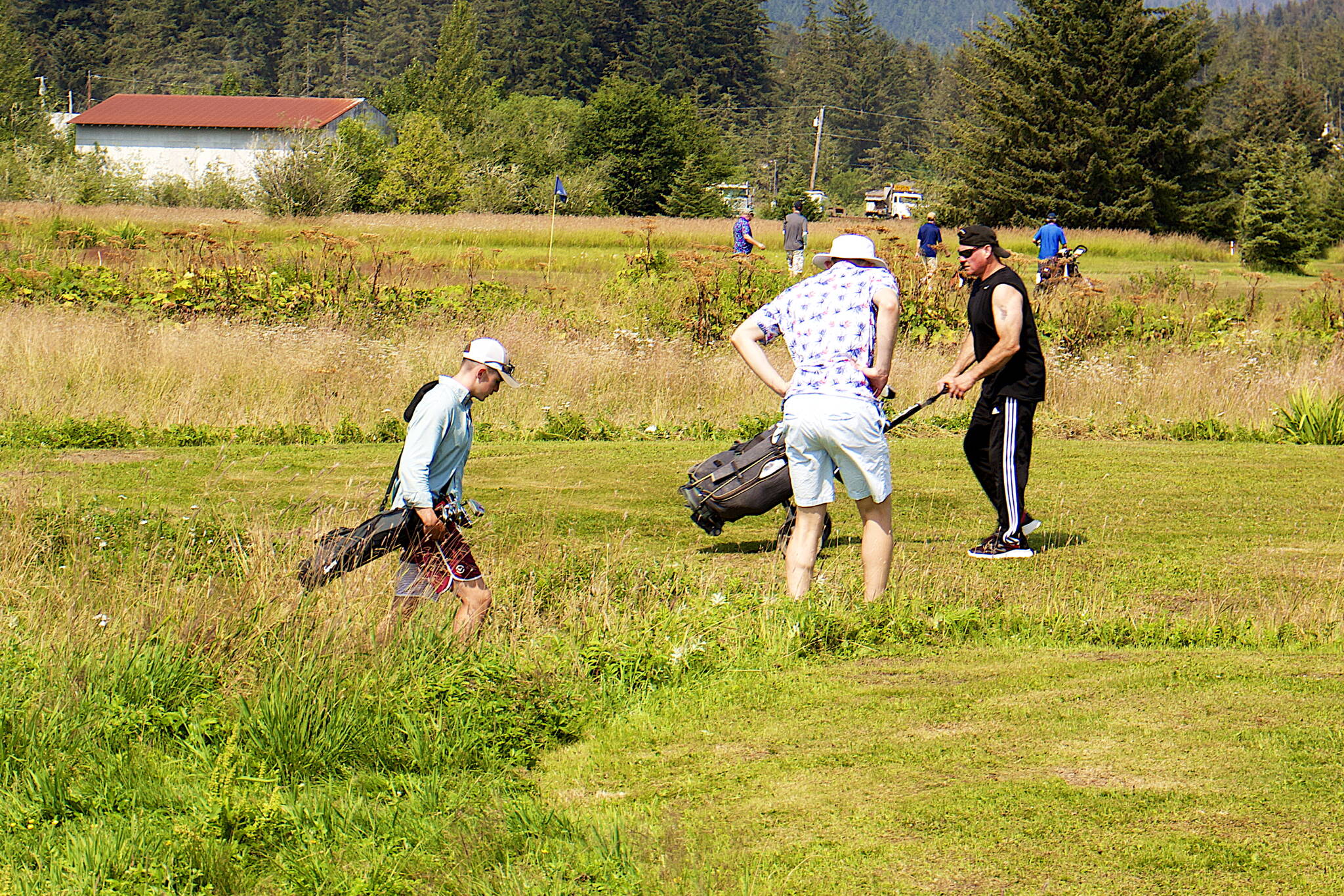 Dylan Williams (left), Matt Seymour (center) and Mark Wendling look for their balls in the rough at the seventh hole of the Annual Greater Juneau Chamber of Commerce Golf Classic on Saturday at the Mendenhall Golf Course. (Mark Sabbatini / Juneau Empire)