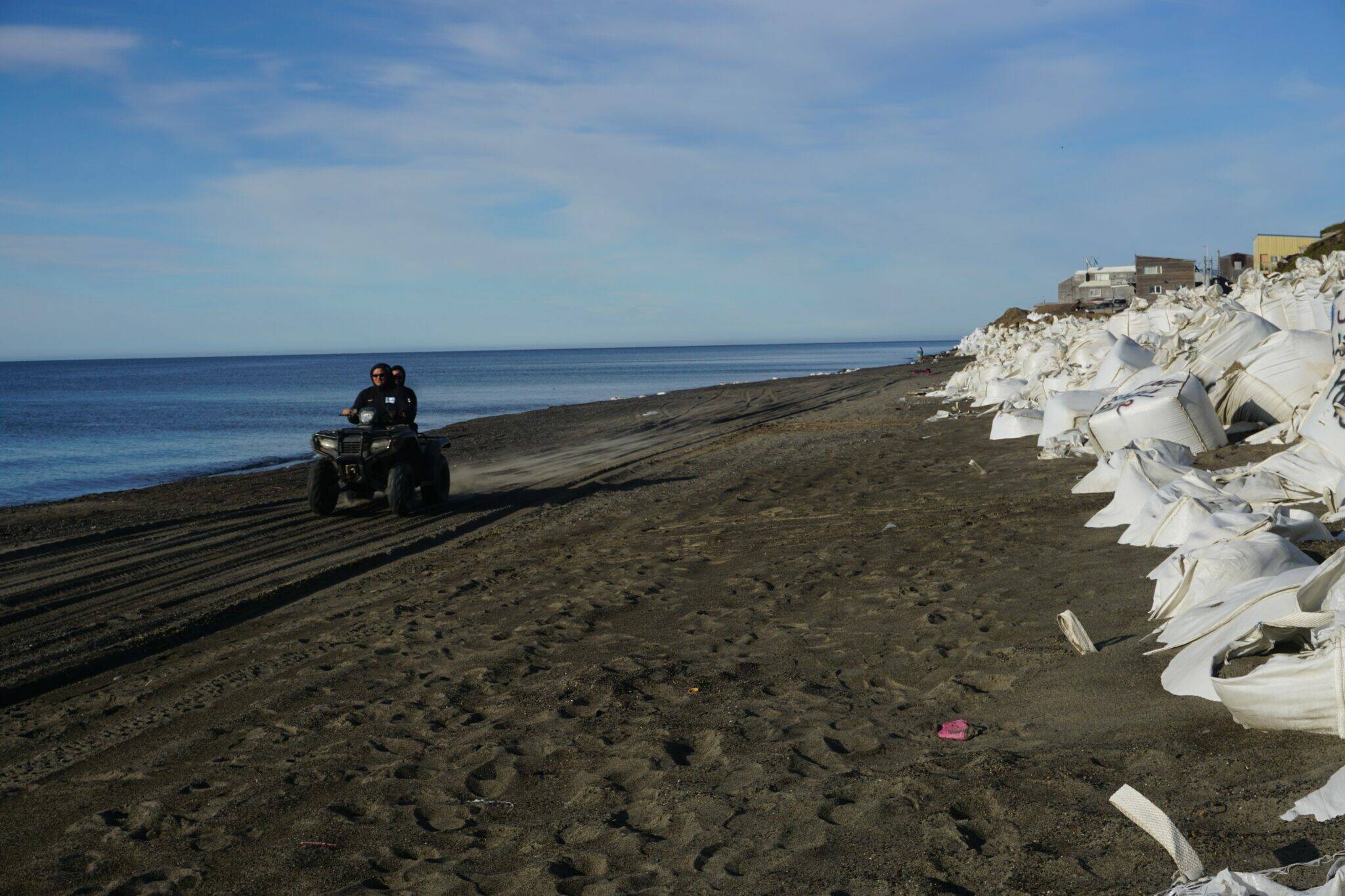 Two people ride an all-terrain vehicle on Utqiagvik’s beach on Aug. 2, 2022. (Photo by Yereth Rosen/Alaska Beacon)