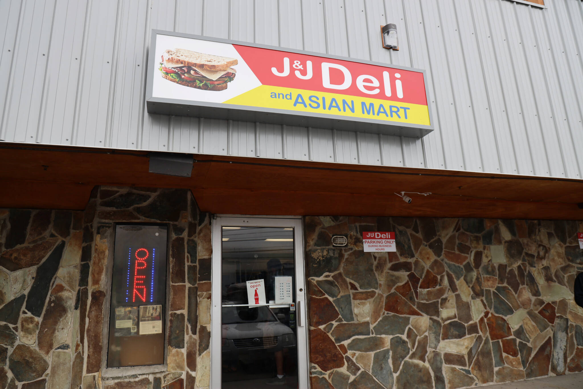 An open sign beams neon colors for the last time Monday afternoon at J&J Deli and Asian Mart. (Clarise Larson / Juneau Empire)