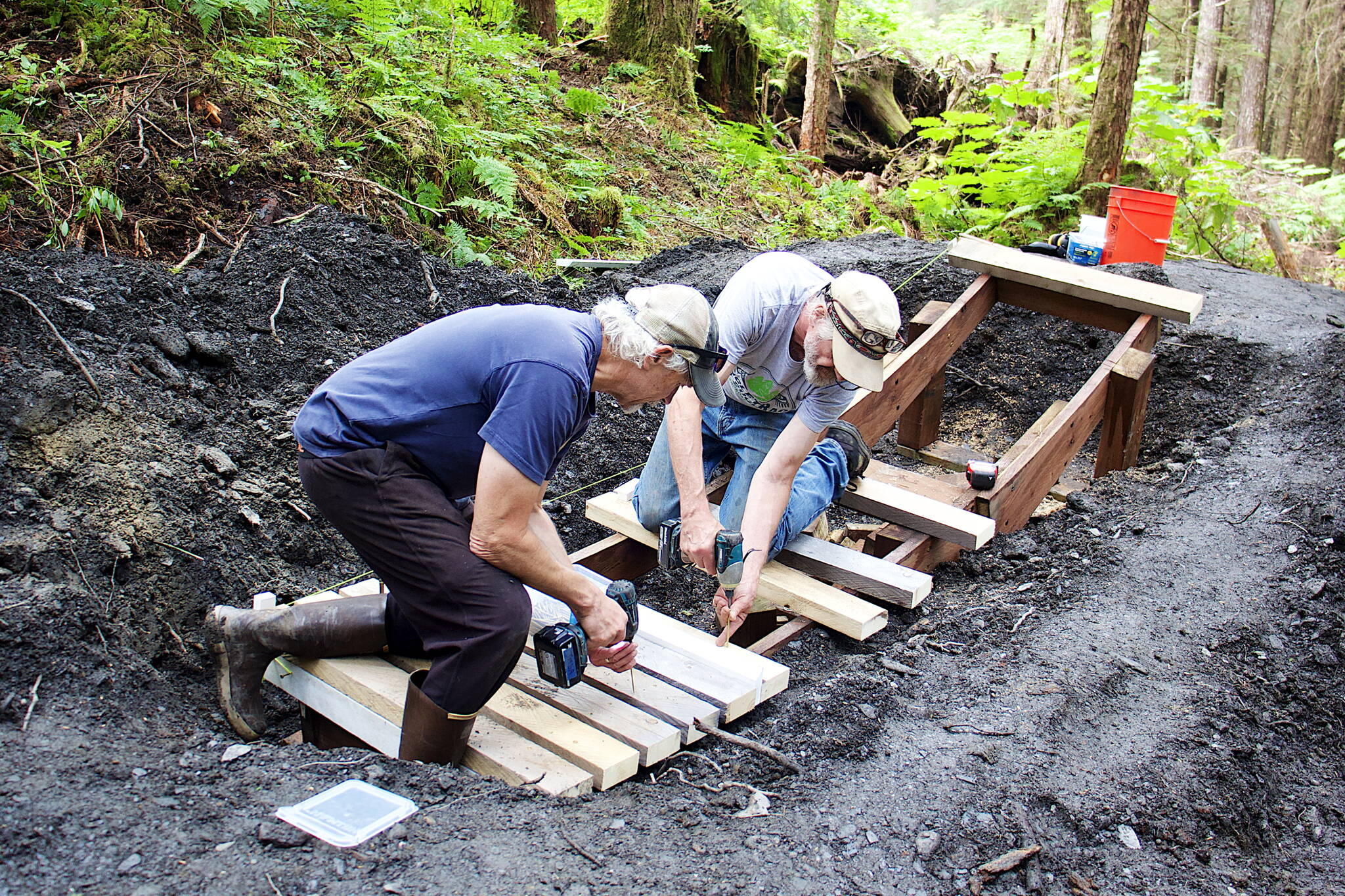 Craig Good (left) and Jim Papoi build a jump along the intermediate-level trail for the new Thunder Mountain Bike Park on Saturday. (Mark Sabbatini / Juneau Empire)