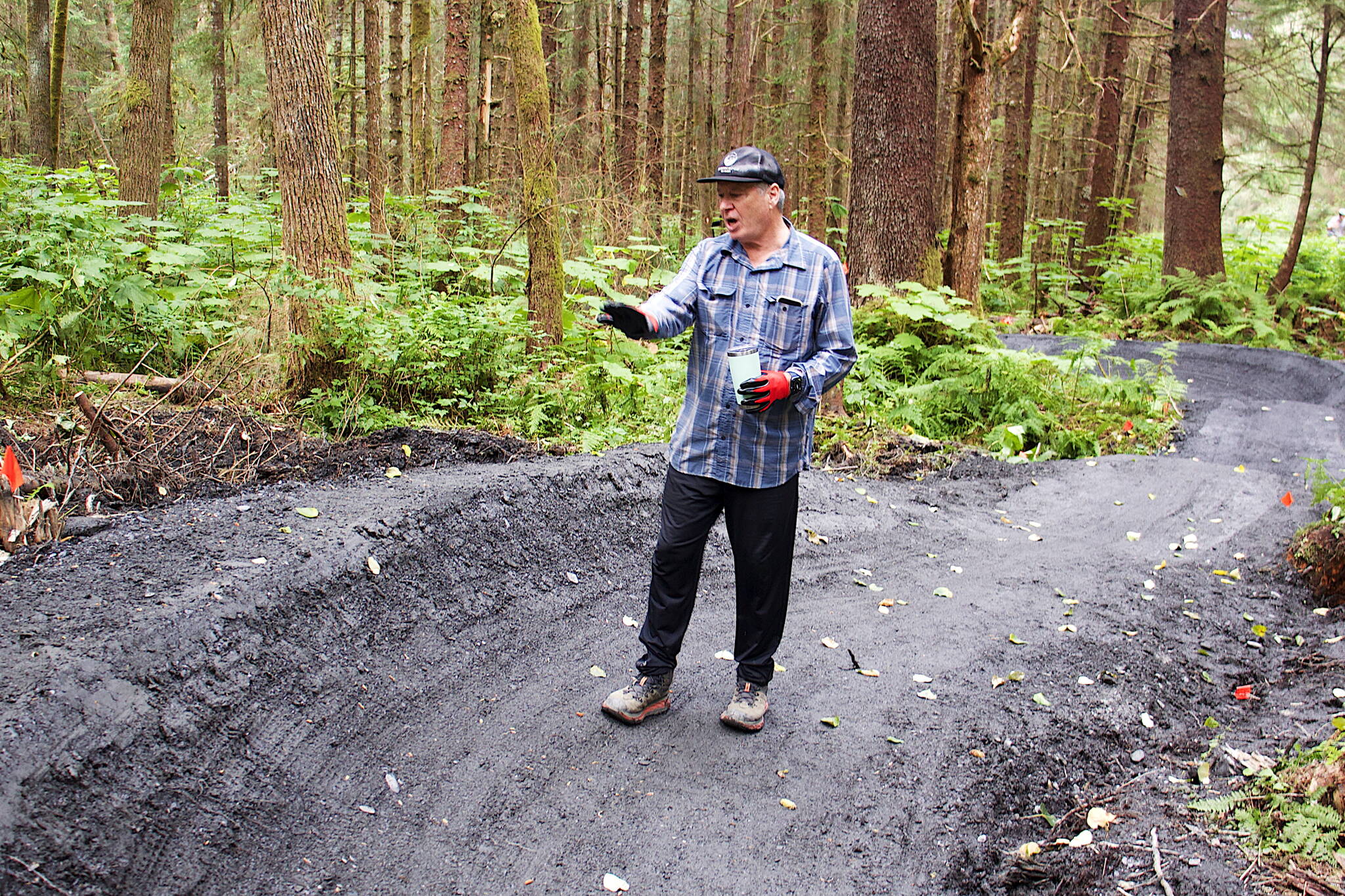 Jack Kreinheder, a board member of both the Juneau Mountain Bike Alliance and Trail Mix, explains the planning process for the turns and other features on the beginner’s trail at the new Thunder Mountain Bike Park on Saturday. (Mark Sabbatini / Juneau Empire)