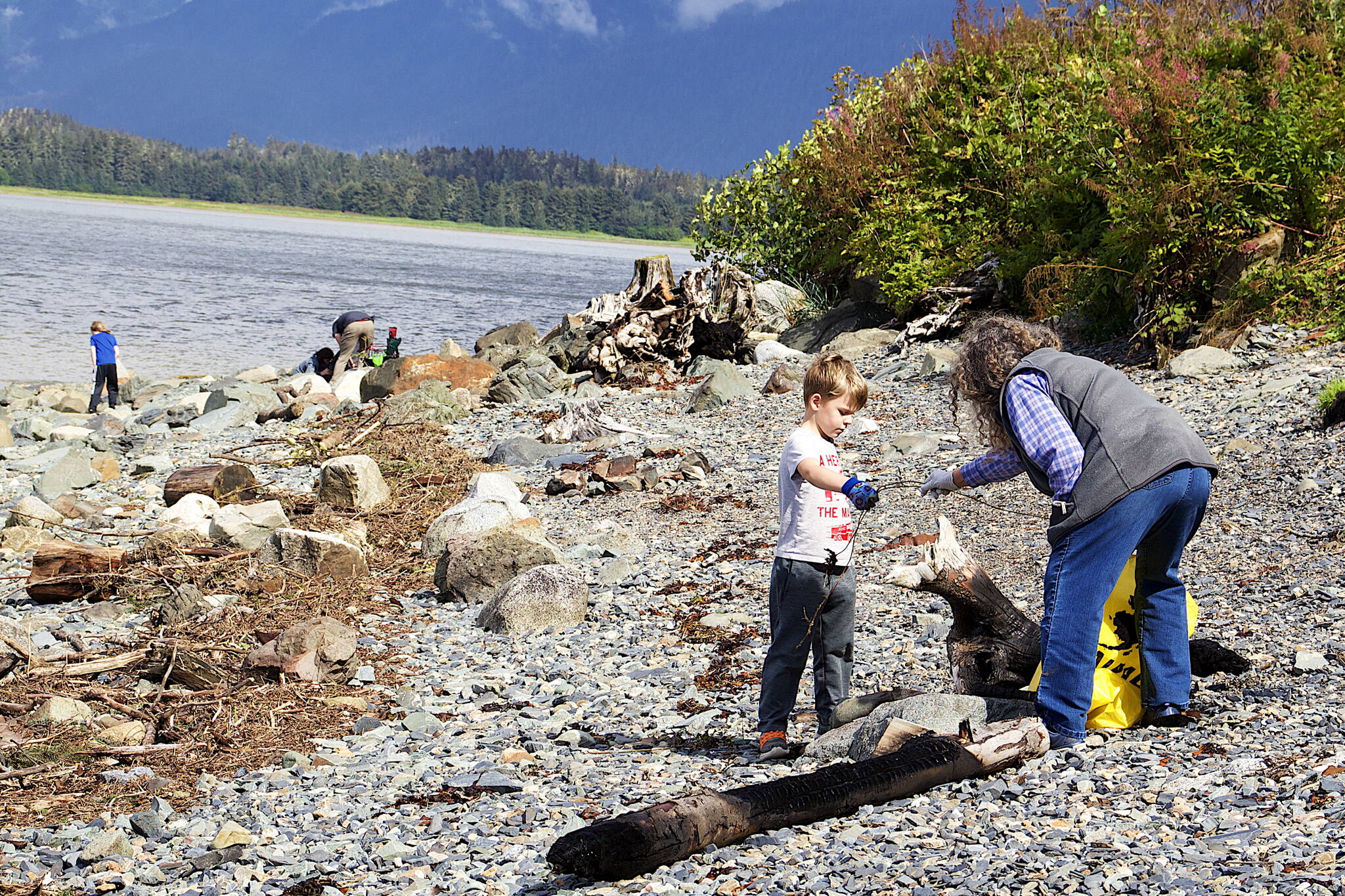 Amos Andreassen, 6, hands a piece of debris to his grandmother, Peggy Tutu, on a beach in North Douglas during a community cleanup Sunday following last weekend’s record flooding of the Mendenhall River. (Mark Sabbatini / Juneau Empire)