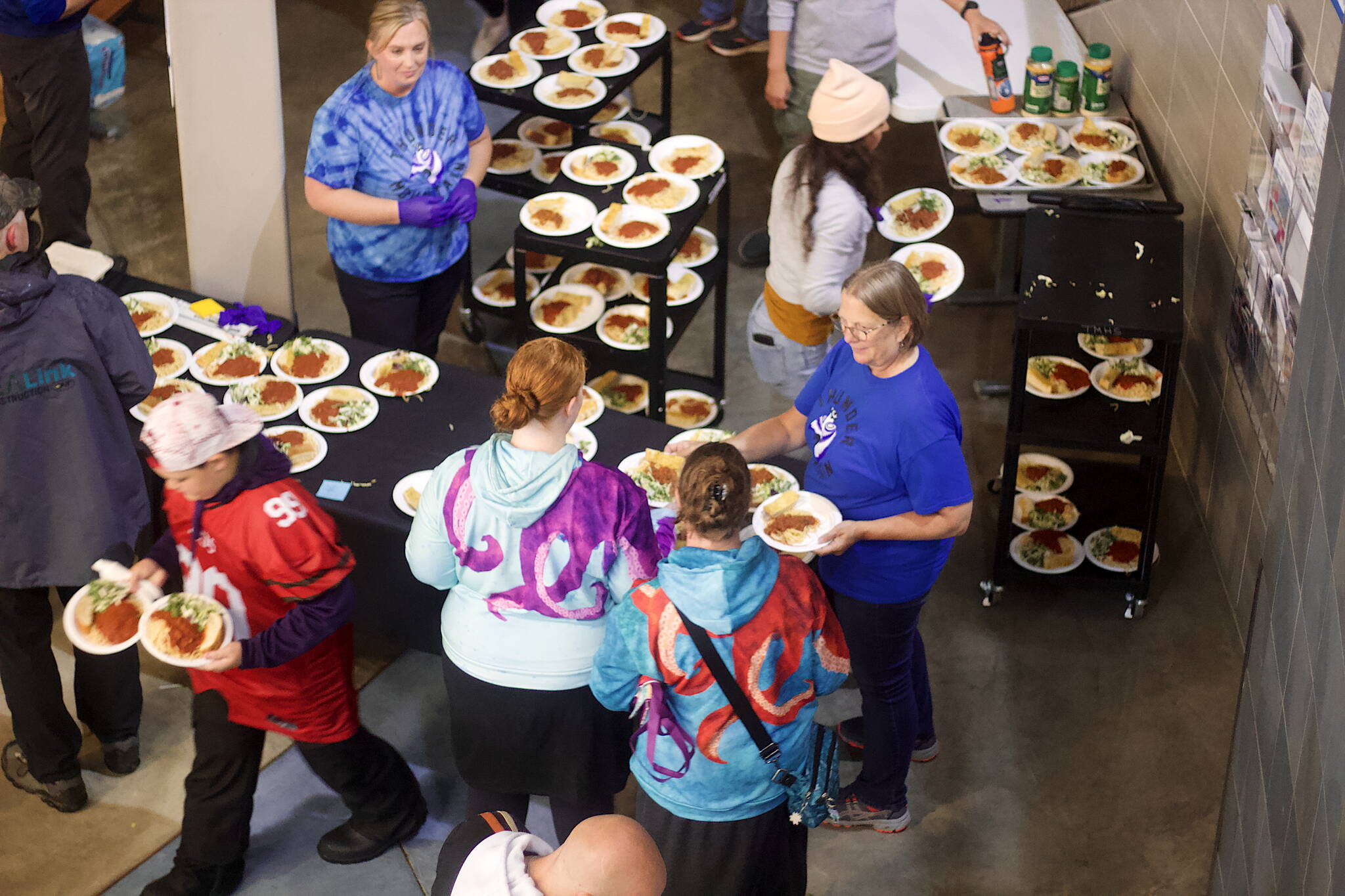 Carol May (right), a teacher at Thunder Mountain High School, hands out plates of food during a fundraising dinner and auction at Saturday night to benefit victims of a flood earlier this month. (Mark Sabbatini / Juneau Empire)