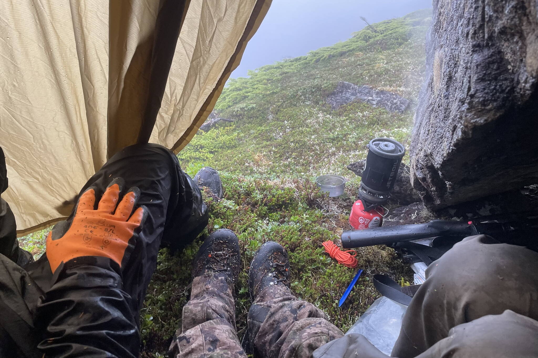 The author, his wife Abby and his friend Danny wait out the weather under a rock and a tarp on opening day of deer season. (Photo by Jeff Lund)