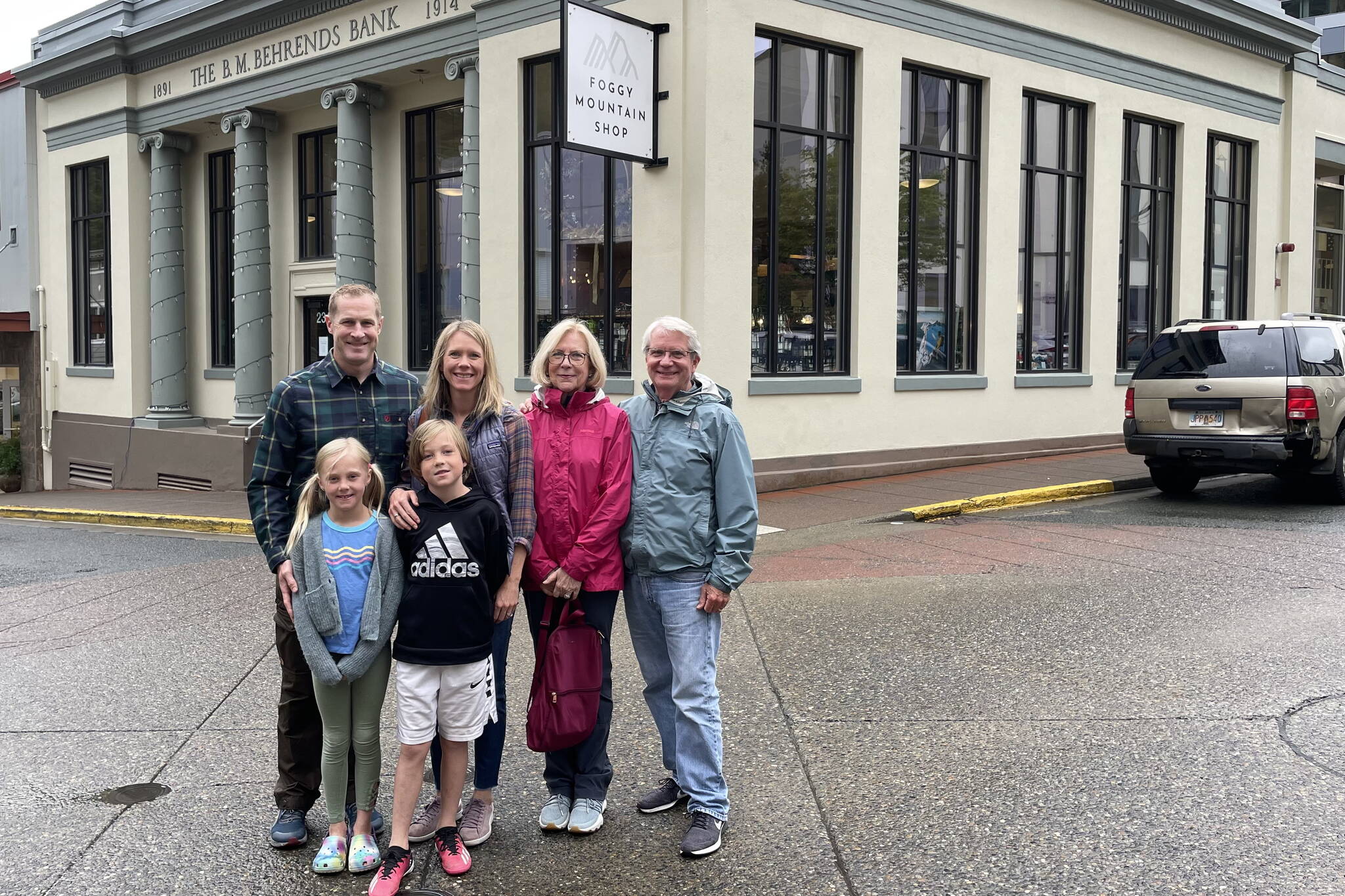 Three generations of the Behrends-Gruening family stand outside the bank founded by B.M. Behrends. Standing from left: Jack Vines, Caroline Gruening Vines, Anne Gruening (great-granddaughter of B.M. Behrends), and Win Gruening (grandson of Governor and Senator Ernest Gruening). Young Norah and Jack Vines stand in front. Photo by Laurie Craig