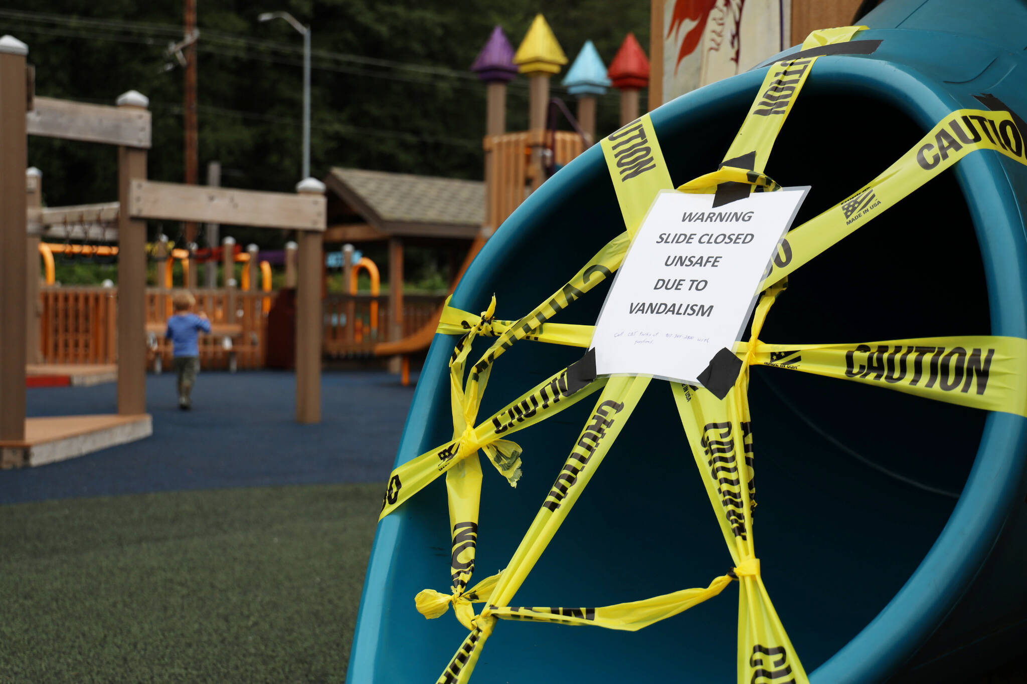Caution tape surrounds the exit of a slide located at the Project Playground at Twin Lakes Park Friday morning. Two slides were vandalized with bear spray earlier this week, resulting in multiple injuries. (Clarise Larson / Juneau Empire)