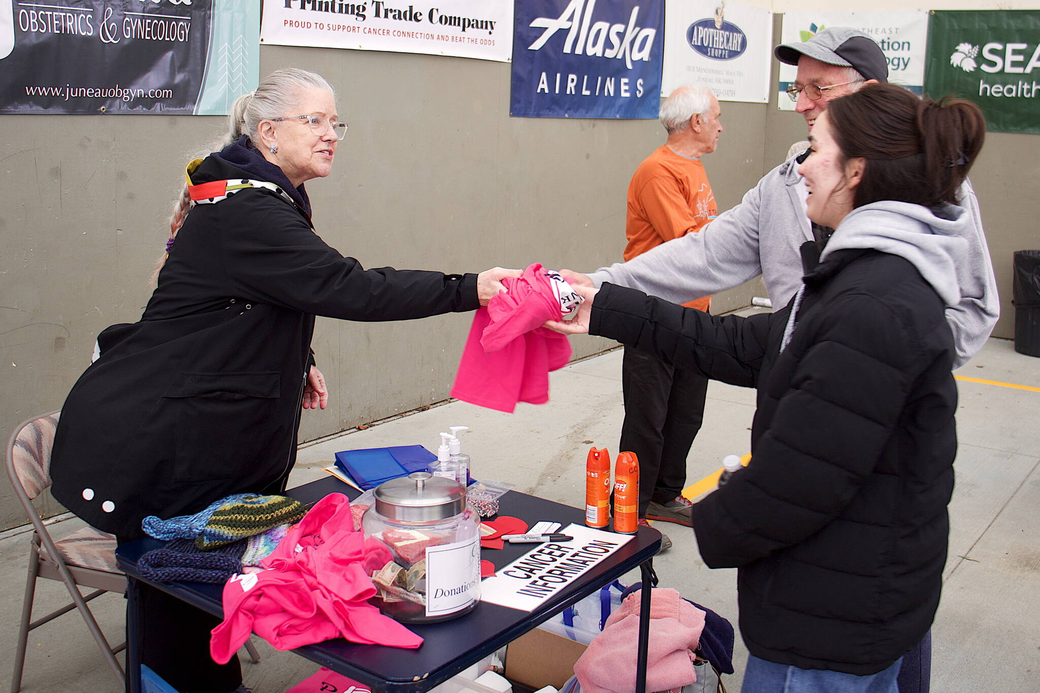 John Eldridge and his daughter, Lisa, 21, get a pink cancer awareness t-shirt from Eileen Hosey, vice president of Cancer Connection, before the start of the 32nd Annual Beat the Odds: A Race Against Cancer event at Kax̱dig̱oowu Héen Elementary School on Saturday morning. The race is a fundraiser for Cancer Connection, which provides services such as travel assistance for people needing treatment outside Juneau. (Mark Sabbatini / Juneau Empire)