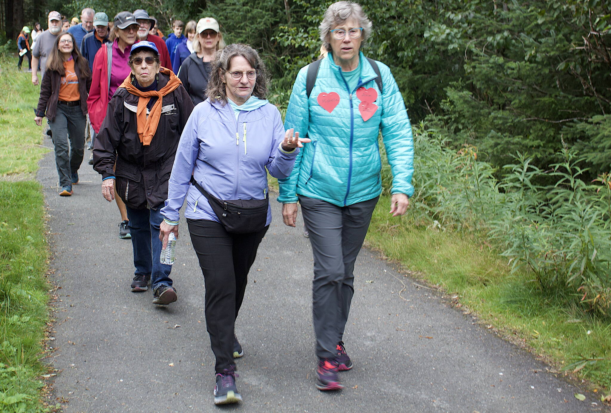 Participants walk the two-mile course, much of it on trails through the woods, during the 32nd Annual Beat the Odds: A Race Against Cancer on Saturday. Many participants wore paper hearts with names signifying loved ones affected by the disease. (Mark Sabbatini / Juneau Empire)