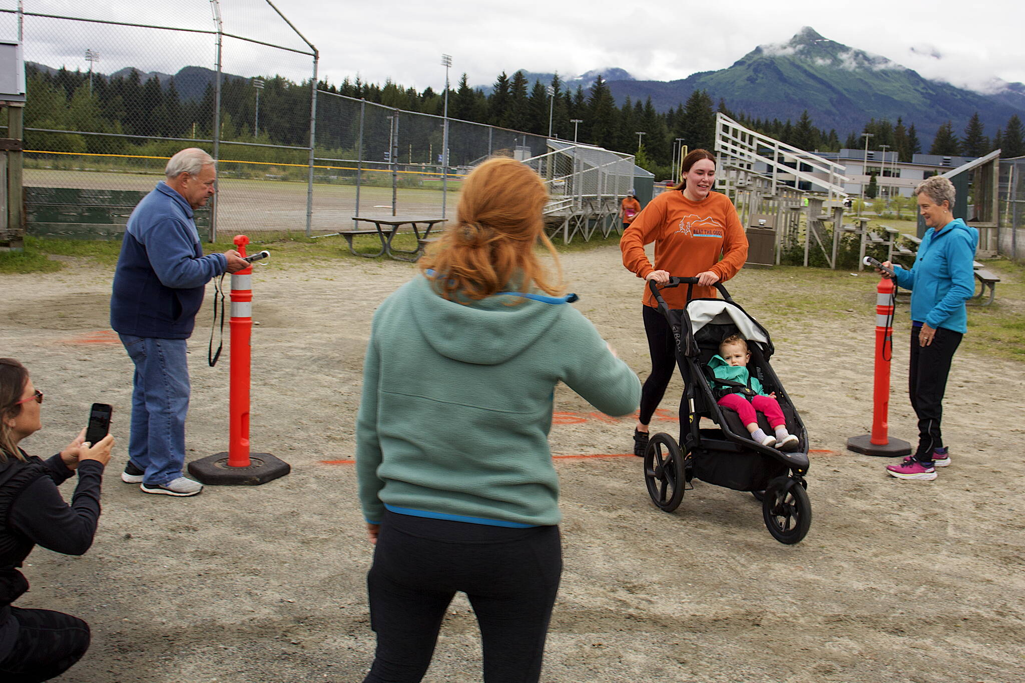 Sarah Clark pushes a stroller with her 16-month-old daughter Faye across the finish line of the 5K course during the 32nd Annual Beat the Odds: A Race Against Cancer that started and ended at Kax̱dig̱oowu Héen Elementary School on Saturday morning. (Mark Sabbatini / Juneau Empire)