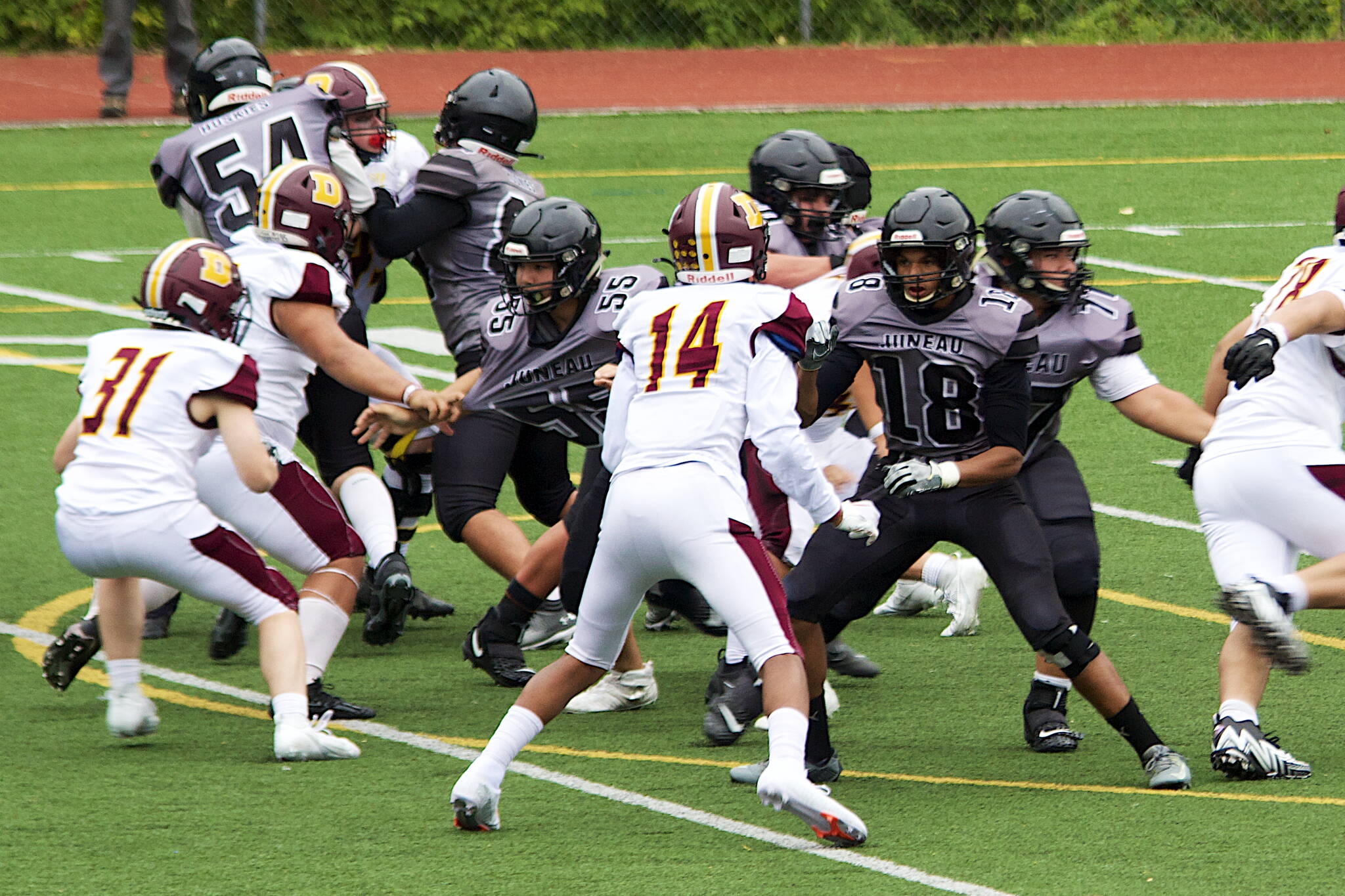 Juneau wide receiver Kenyon Jordan tries to block a Dimond High School defender as lineman Walter Haube-Law (55) is grabbed by the jersey Saturday afternoon at Adair-Kennedy Field. (Mark Sabbatini / Juneau Empire)