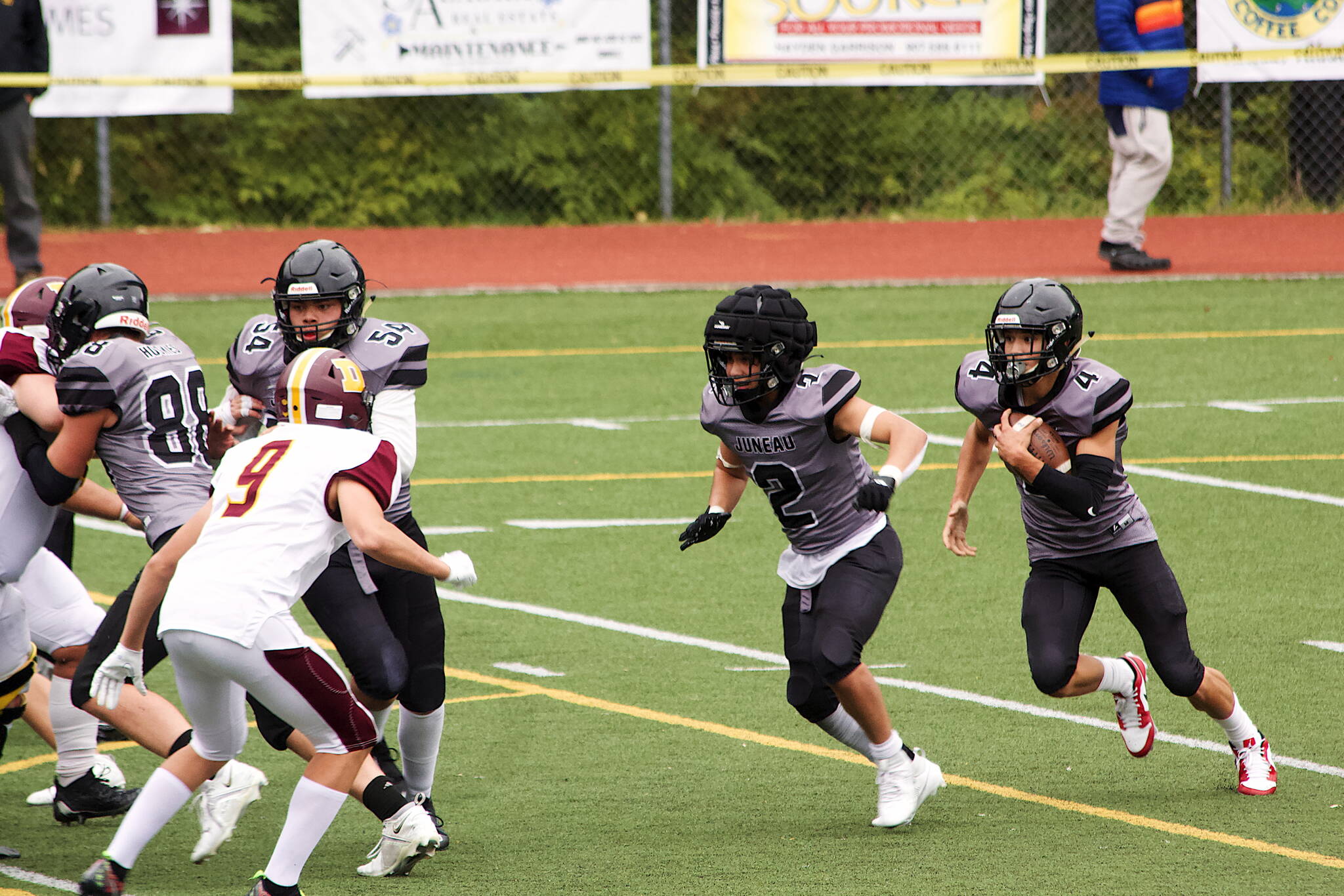Jayden Johnson (4) looks for running room behind Hayden Aube (2) in the second quarter in the Juneau Huskies’ game against the Dimond High School Lynx on Saturday at Adair-Kennedy Field. Johnson had 286 all-purpose yards and four touchdowns for the Huskies. (Mark Sabbatini / Juneau Empire)
