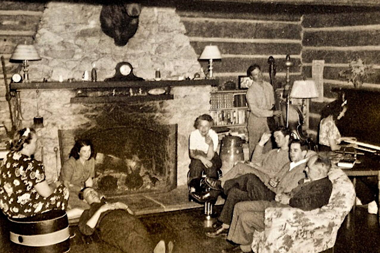 A group of people gather in front of the stone fireplace at Taku Lodge including Leigh Hackley “Hack” Smith, who inherited one-quarter of the estate from his grandparents at age nine, his mother Erie Smith next to fireplace on the right and Mary Joyce who took over the lodge when “Hack” died in 1934. (Courtesy of Ken and Mic Ward)