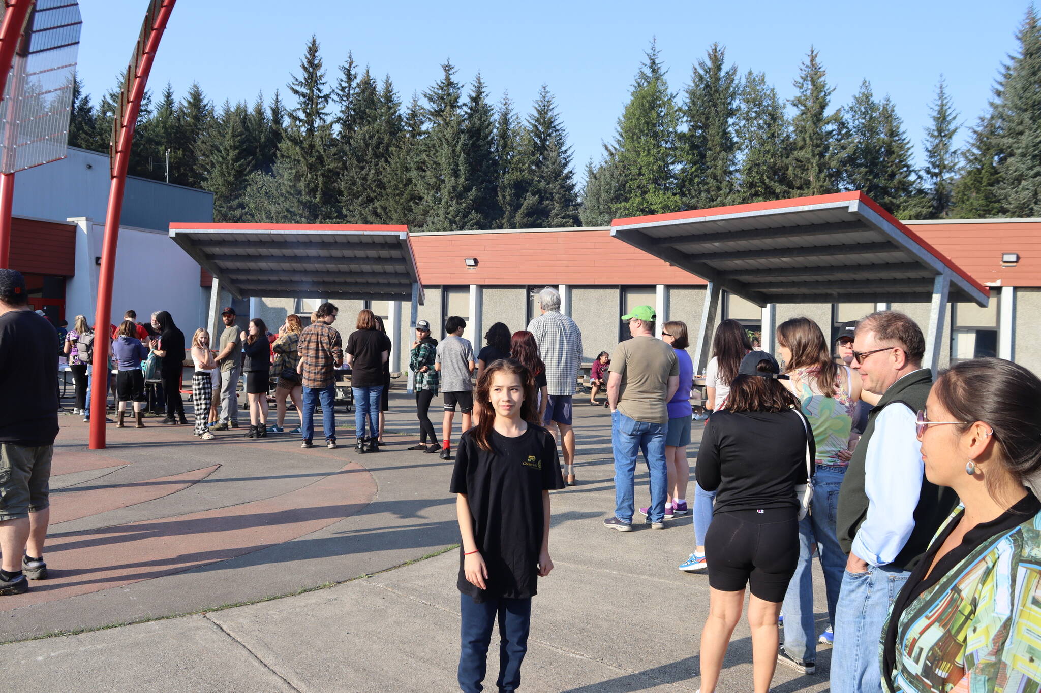 Rosemarie Becker looks toward the parking lot during Floyd Dryden Middle School’s 50th anniversary celebration Wednesday. Her father, Ed Becker, looks on as they wait in the hot dog line. (Meredith Jordan / Juneau Empire)