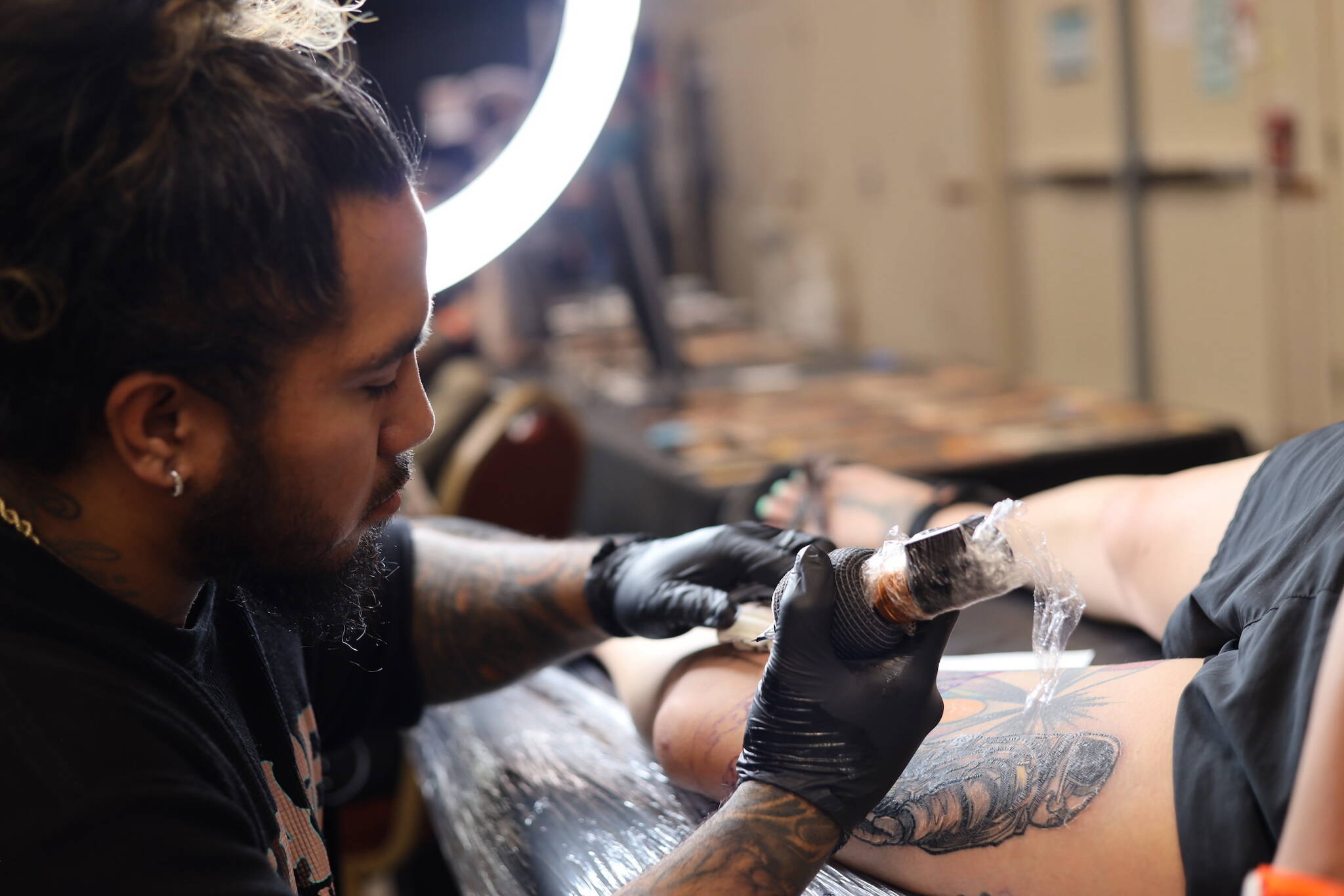 Kiko Valladolid, an artist originally from Kodiak, tattoos a spaceship on Juneau resident Tara Hansen's “galaxy leg" Thursday afternoon at Elizabeth Peratrovich Hall during the Ink Masters Tattoo Show. (Clarise Larson / Juneau Empire)