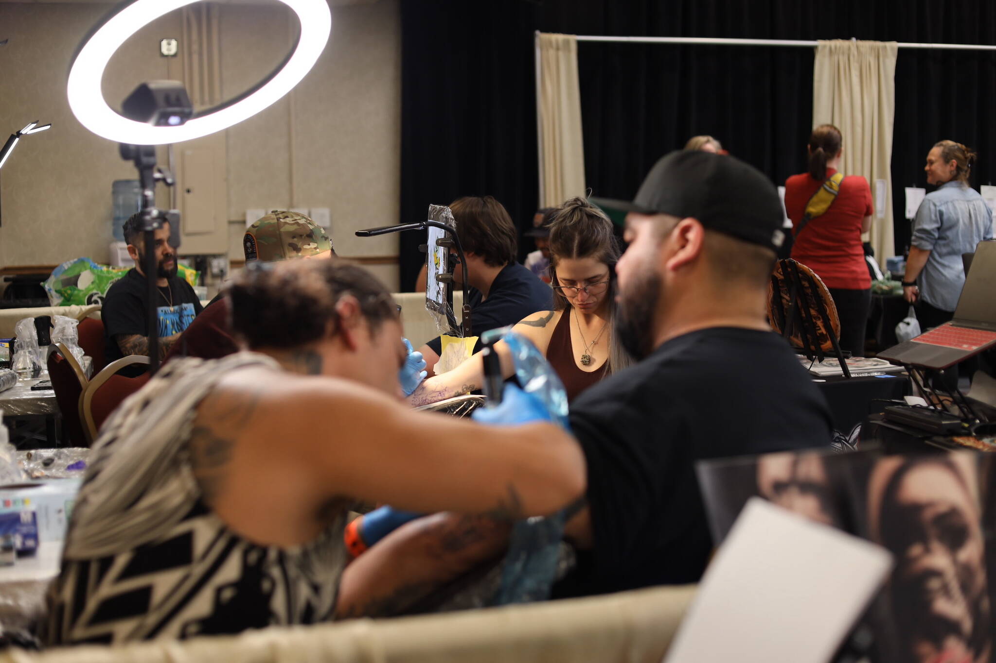 Rows of artists tattoo clients Thursday afternoon at Elizabeth Peratrovich Hall during the Ink Masters Tattoo Show. (Clarise Larson / Juneau Empire)