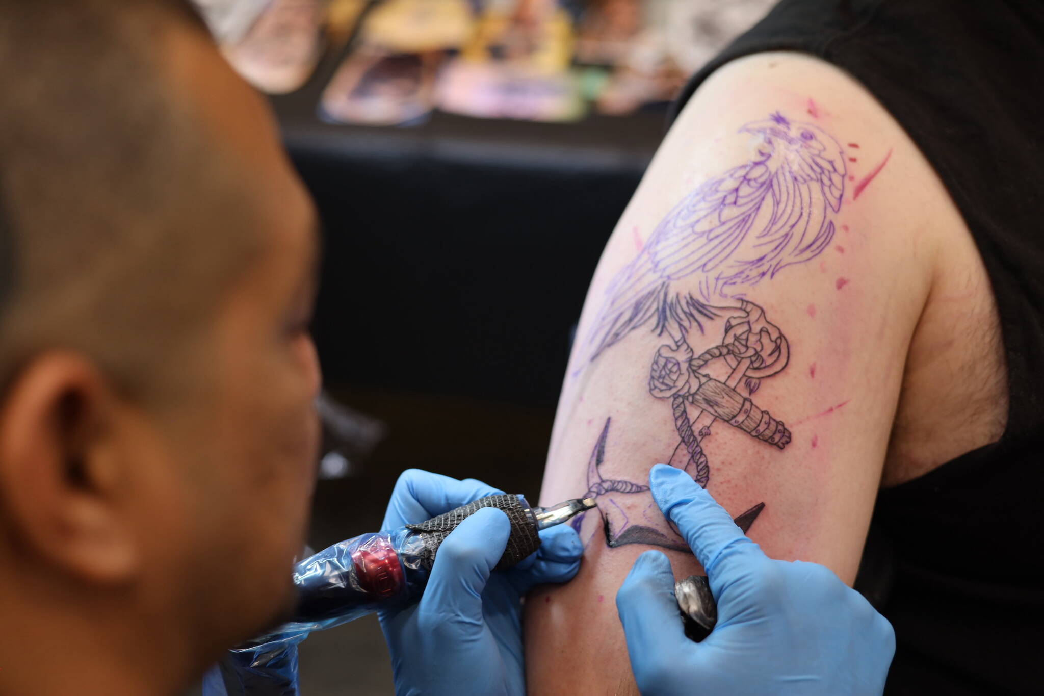 Ricardo Galindo tattoos a raven onto Juneau resident Sky Martin on Thursday afternoon at Elizabeth Peratrovich Hall during the Ink Masters Tattoo Show. (Clarise Larson / Juneau Empire)
