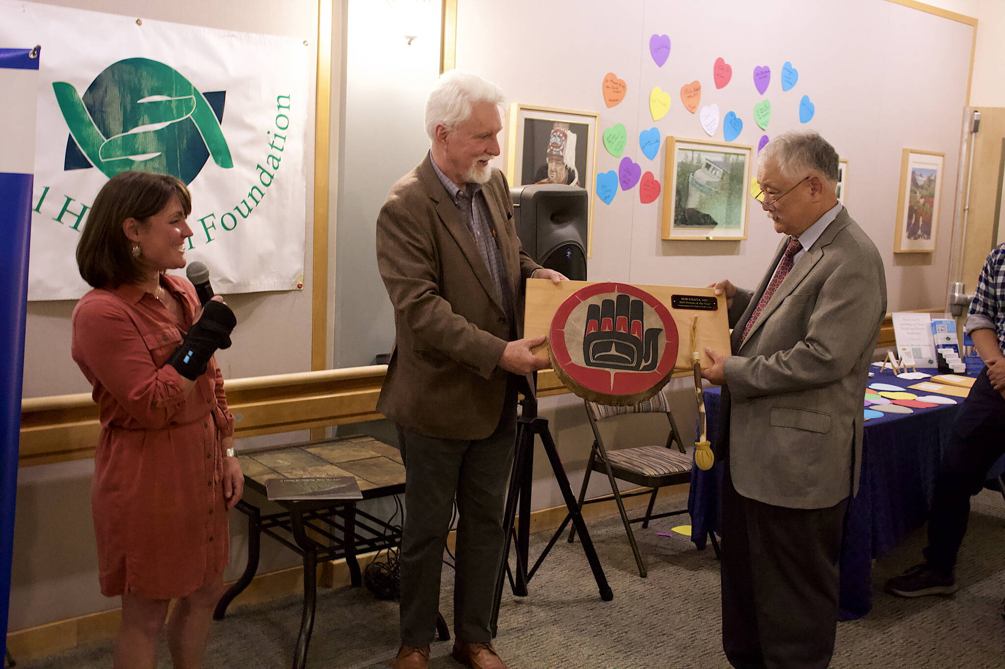Bob Urata (right), a doctor credited with establishing and growing hospice care in Juneau, is presented with the “Person of the Year” award by the Foundation for End of Life Care by Hal Geiger, a member of Bartlett Regional Hospital’s board of directors during a ceremony on Thursday. Seanna O’Sullivan (left), president of the foundation, said Urata was an essential presence for her family after her husband was diagnosed with a fatal illness. (Mark Sabbatini / Juneau Empire)