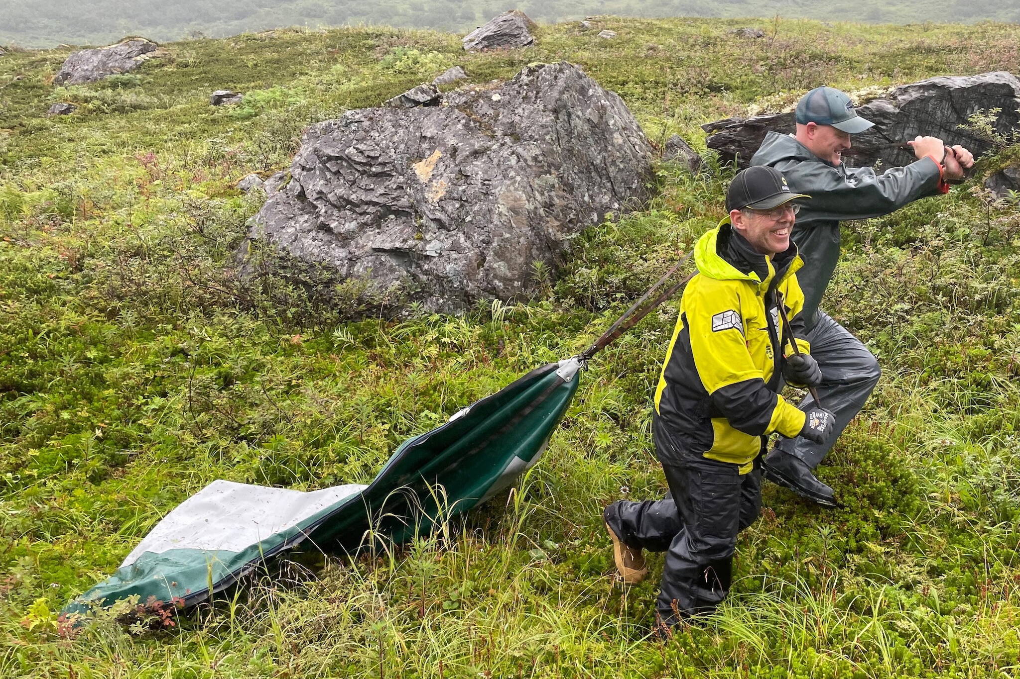 Gerry Hatcher, left, and Drake Singleton drag a deflated boat pontoon over wet vegetation to reach Allison Lake near Valdez. (Photo by Ned Rozell)