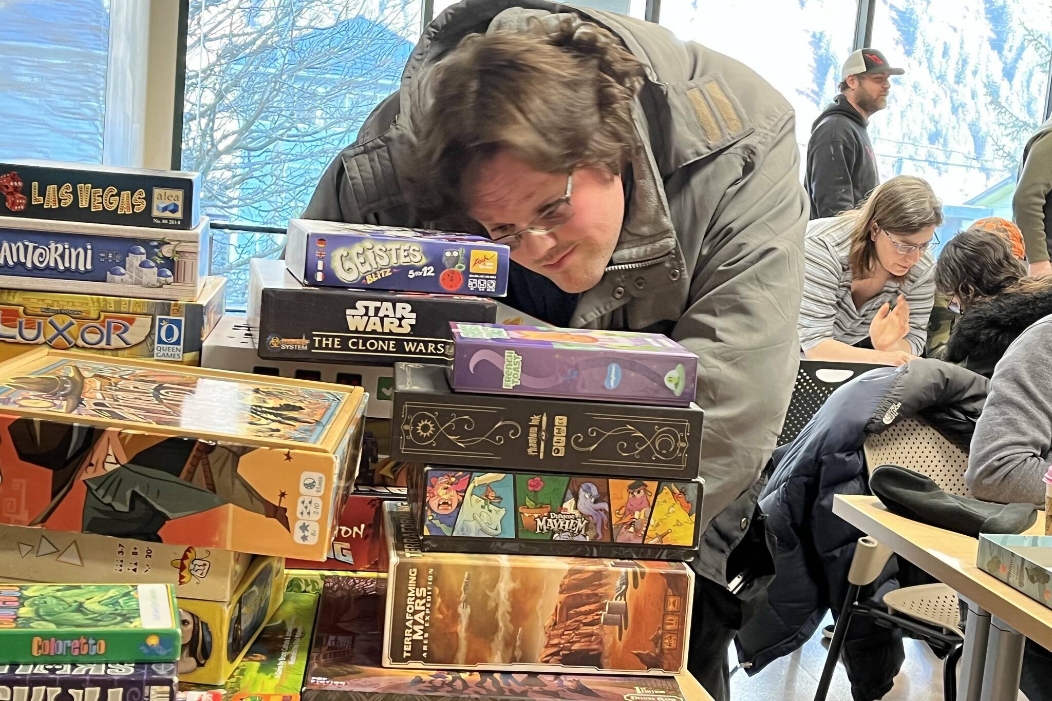 David Holmes digs through a pile of board games during Platypus Gaming’s two-day mini-con at Douglas Public Library on Jan. 28. The full convention is scheduled to take place this weekend, the first time ever in September, following the reopening of Centennial Hall. (Jonson Kuhn / Juneau Empire File)