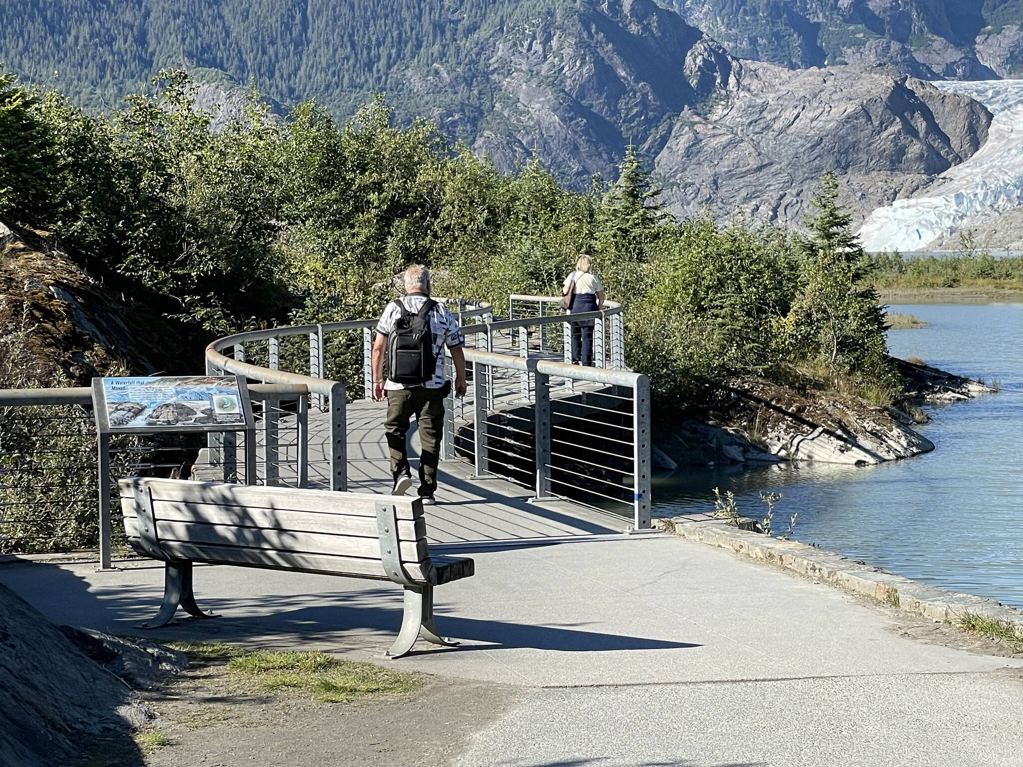Two visitors walk on Photo Point Trail footbridge on a sunny day with normal lake level conditions of about five feet on Aug. 27, 2023. (Photo by Laurie Craig)