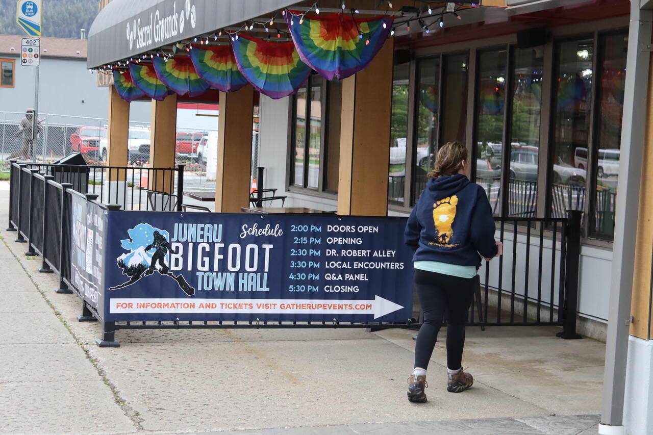 A woman wearing a sweatshirt with a giant footprint enters the Juneau Bigfoot Town Hall at Elizabeth Peratrovich Hall on Friday. (Meredith Jordan / Juneau Empire)