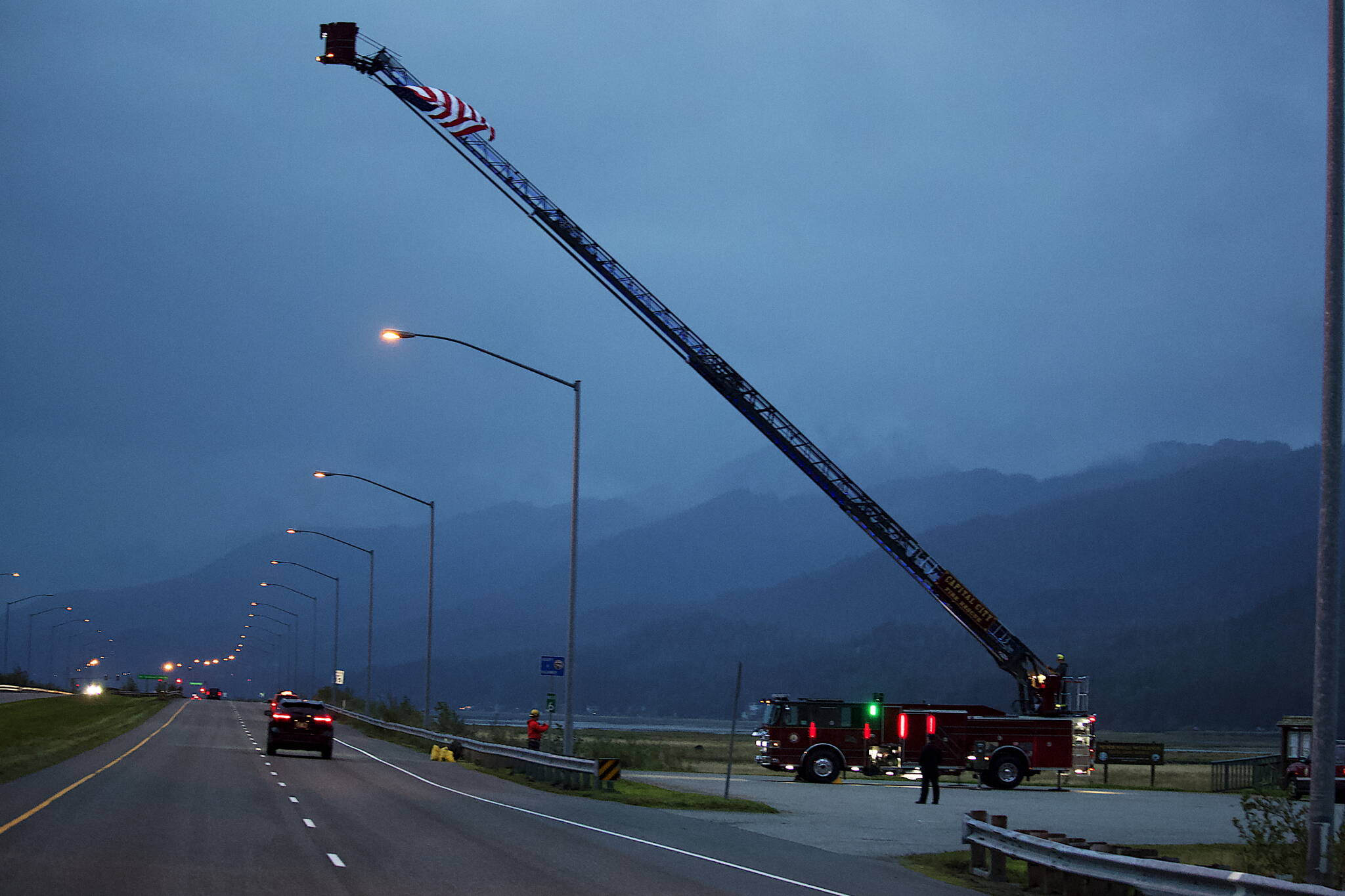 A lit-up Capital City Fire/Rescue truck hoists a flag over Egan Drive on Monday morning to commemorate the Sept. 11, 2001, terrorist attacks. (Mark Sabbatini / Juneau Empire)
