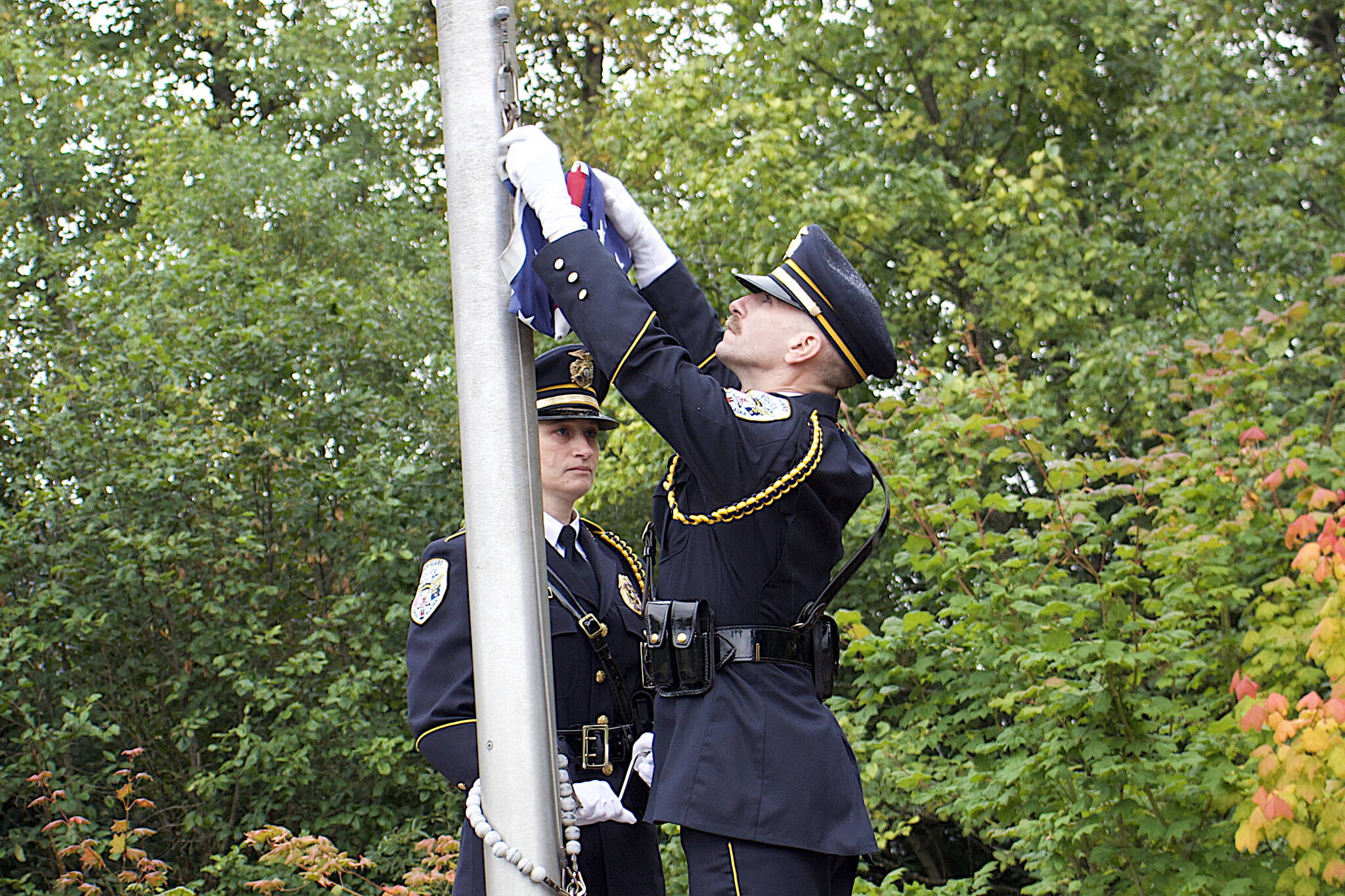 Mattie and Ron Shriver of the Juneau Police Department prepare to hoist the flag to half-mast during a ceremony Monday at the September 11th Memorial at Riverside Rotary Park commemorating the terrorist attacks on that date in 2001. (Mark Sabbatini / Juneau Empire)