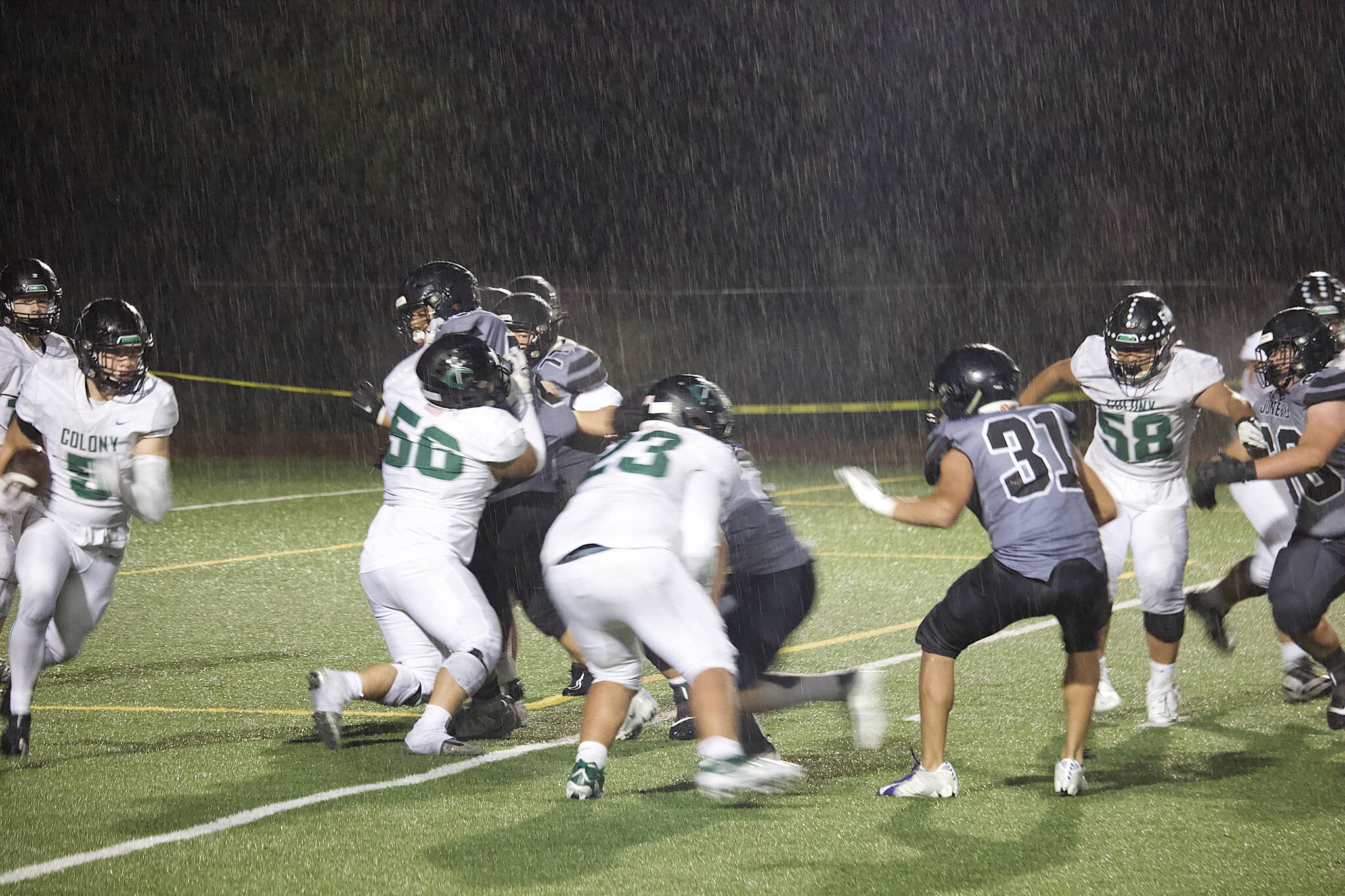 Colony High School running back Bryce Guzman (5) looks for room to run in a downpour during Friday night’s game against the Juneau Huskies at Adair-Kennedy Field. (Mark Sabbatini / Juneau Empire)