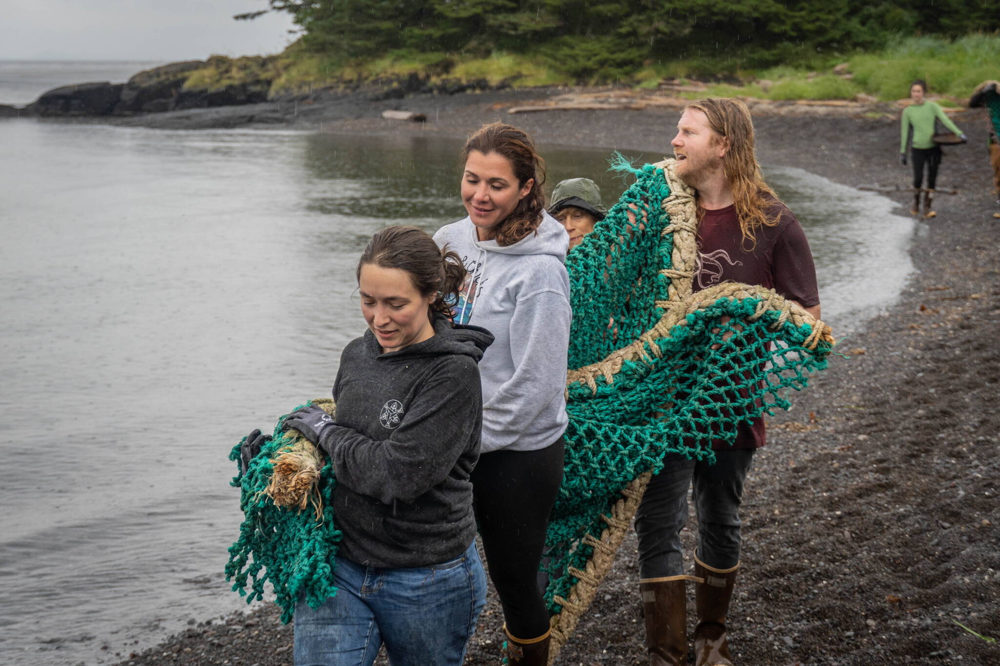 Participants in the 38th Annual International Coastal Cleanup carry a fishnet to a boat on a coast near Sitka in August. (Ryan Morse / Sitka Conservation Society)