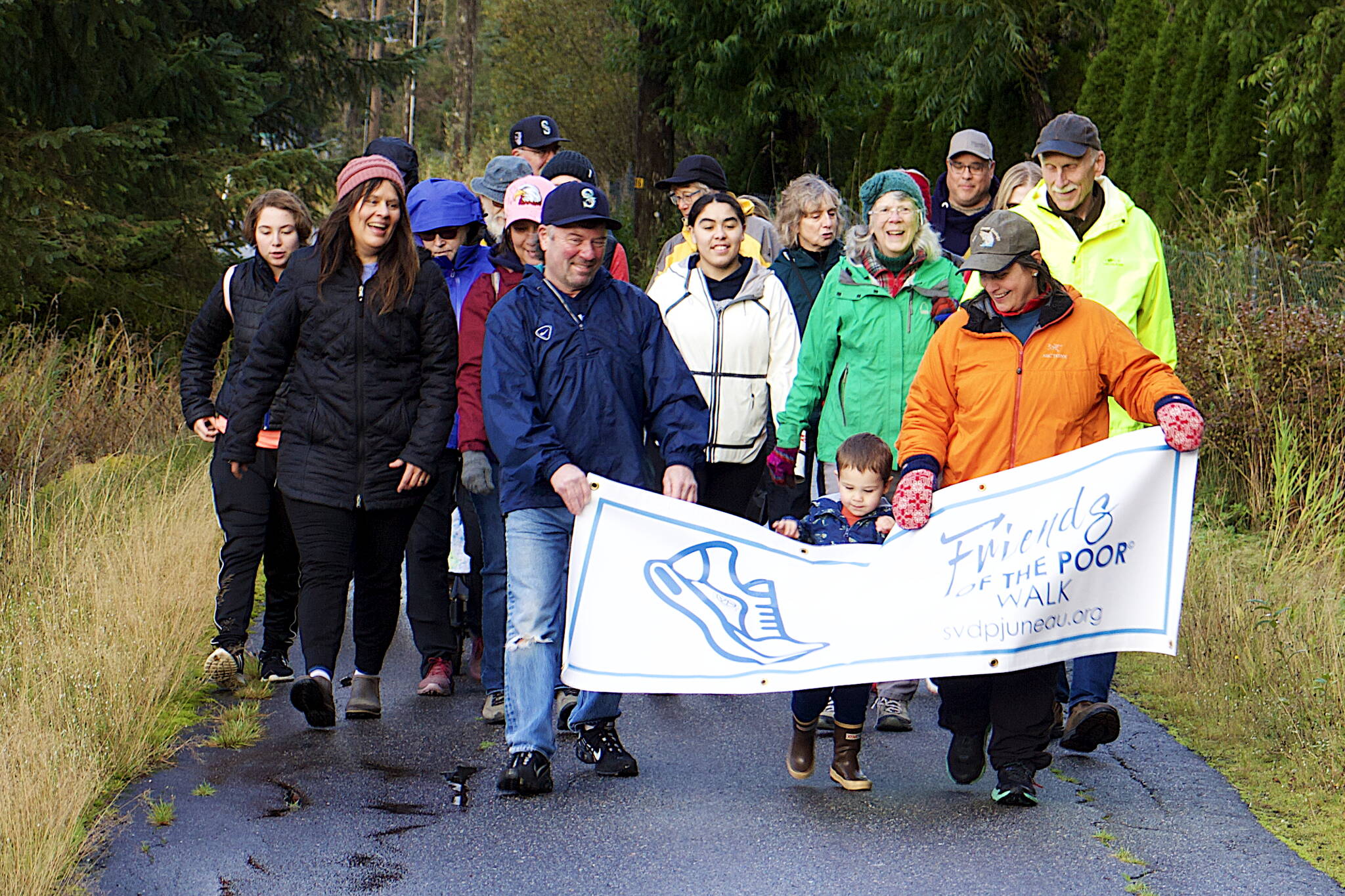 Officials, volunteers and donors affiliated with St. Vincent de Paul Juneau walk down a path alongside Egan Drive on Saturday morning as part of a Friends of the Poor Run/Walk to raise money for the facility and its programs. (Mark Sabbatini / Juneau Empire)