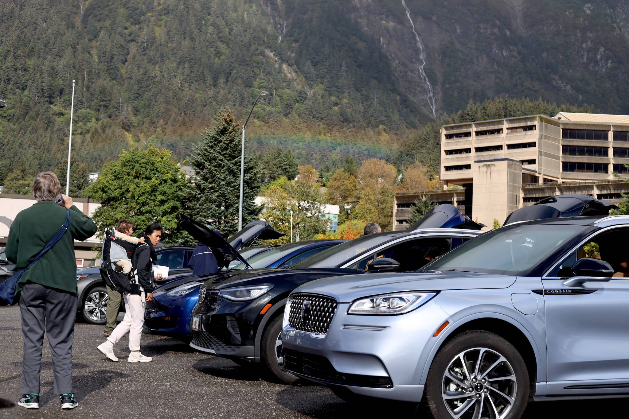 A rainbow appears over downtown as residents check out rows of electric vehicles at Juneau’s EV E-bike Roundup Saturday afternoon. (Clarise Larson / Juneau Empire)
