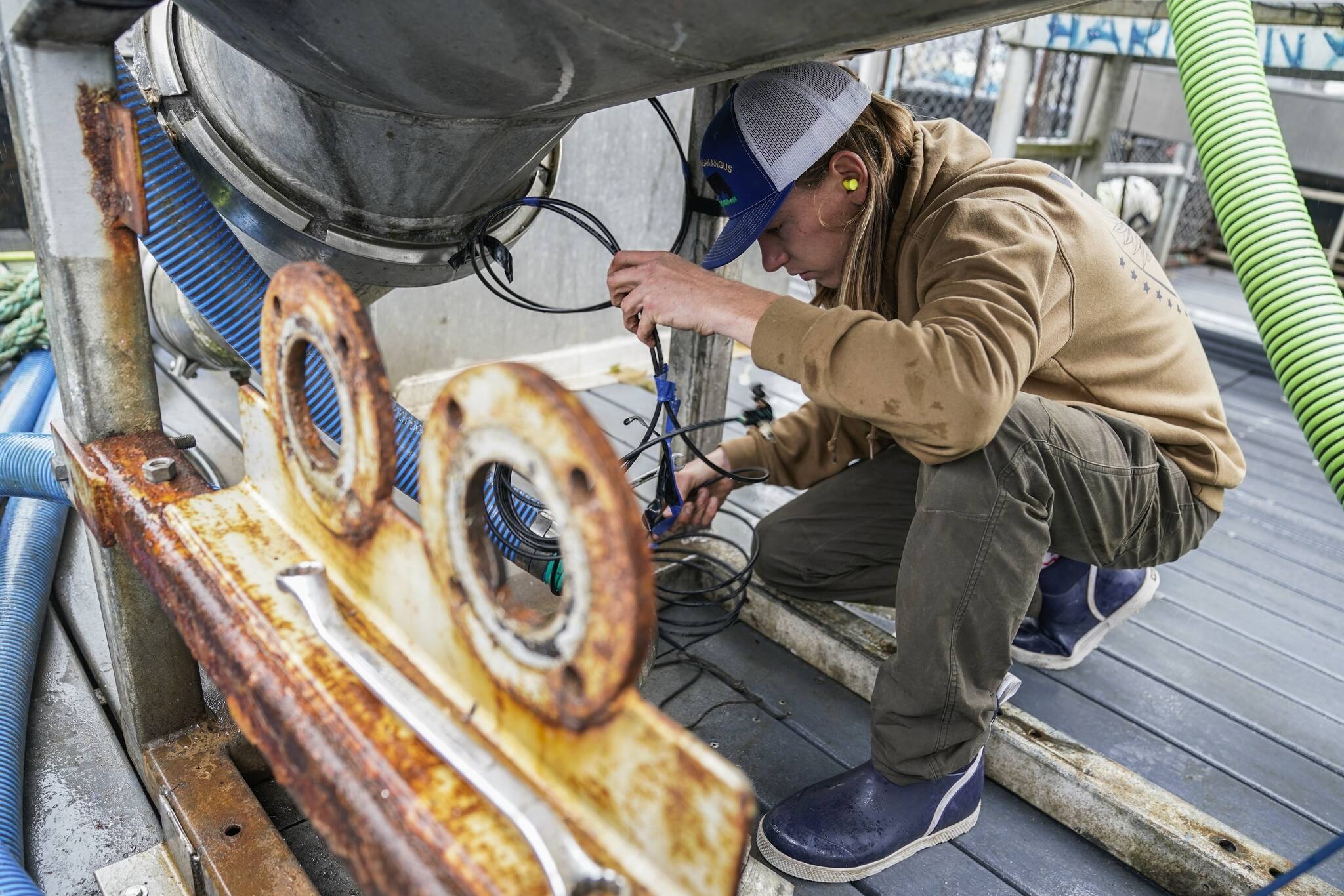 Lane Bolich, captain of the Harmony, reattaches a new hose for the boat’s tendering tanks, Saturday, June 24, 2023, in Kodiak, Alaska. After working as a deckhand for two years, he took the wheel as captain this year at just 20 years old. (AP Photo/Joshua A. Bickel)