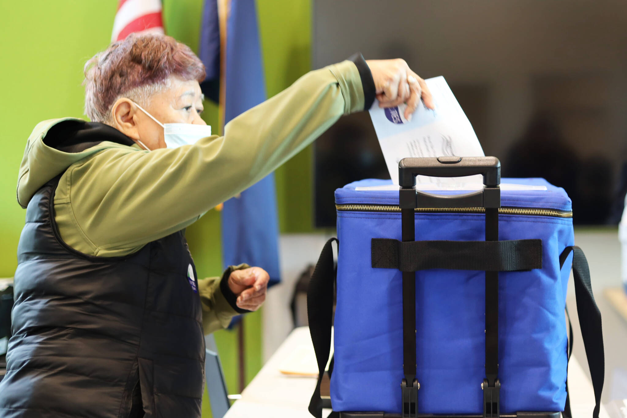 Editha Harris drops her ballot in the ballot box at the voter center located at the Mendenhall Valley Public Library on Tuesday afternoon. (Clarise Larson / Juneau Empire)
