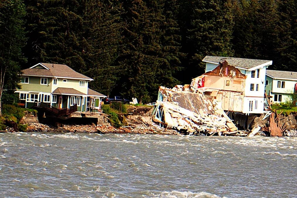 A home hangs over the edge of an eroded riverbank after part of the neighboring house fell into the Mendenhall River during the record flooding of Suicide Basin on Aug. 5. The rest of the second home was later demolished. (Mark Sabbatini / Juneau Empire File)
