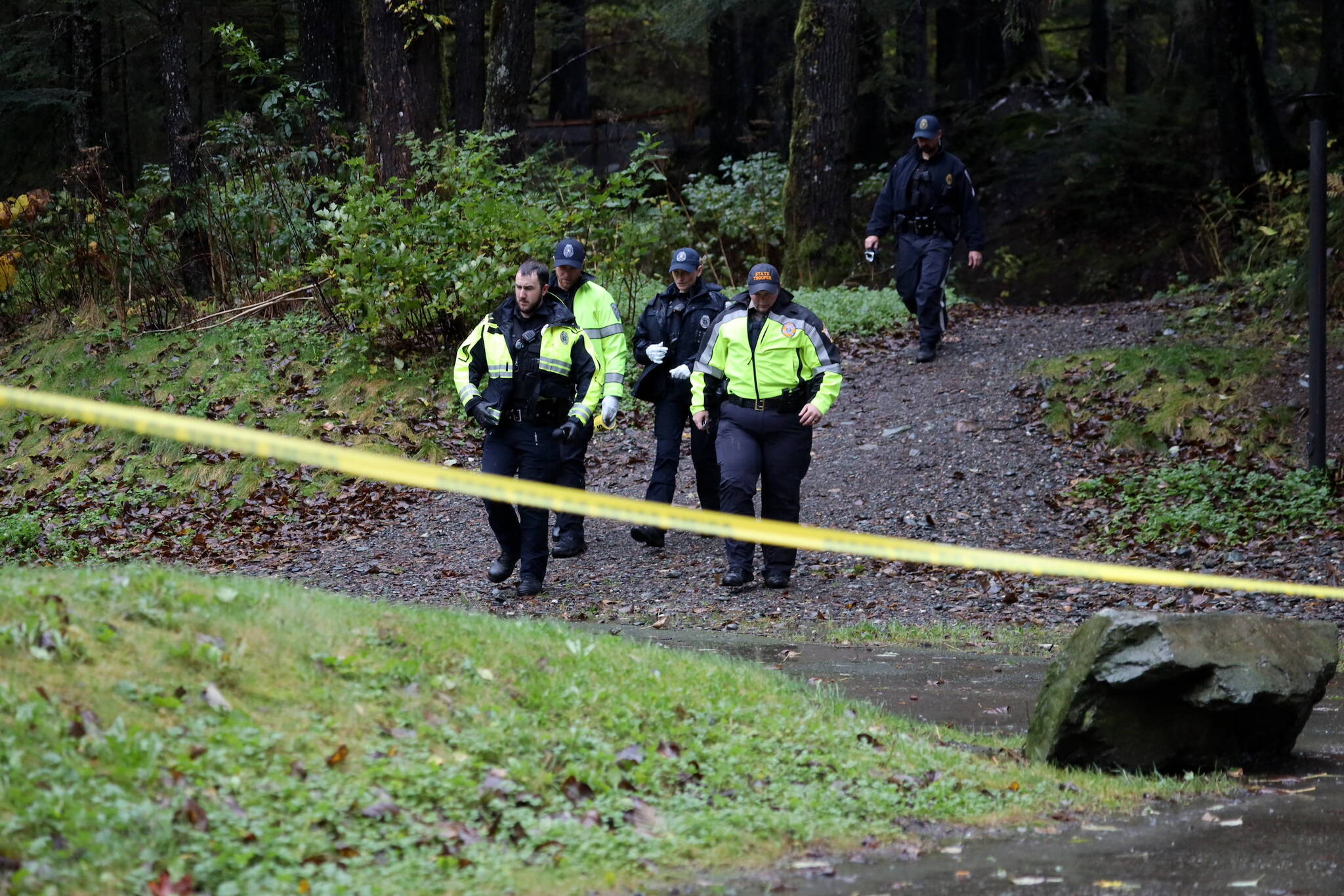 Juneau Police Department and Alaska State Troopers officials walk toward the Cope Park parking lot Monday afternoon. A death investigation is underway following the discovery of a body. (Clarise Larson / Juneau Empire)