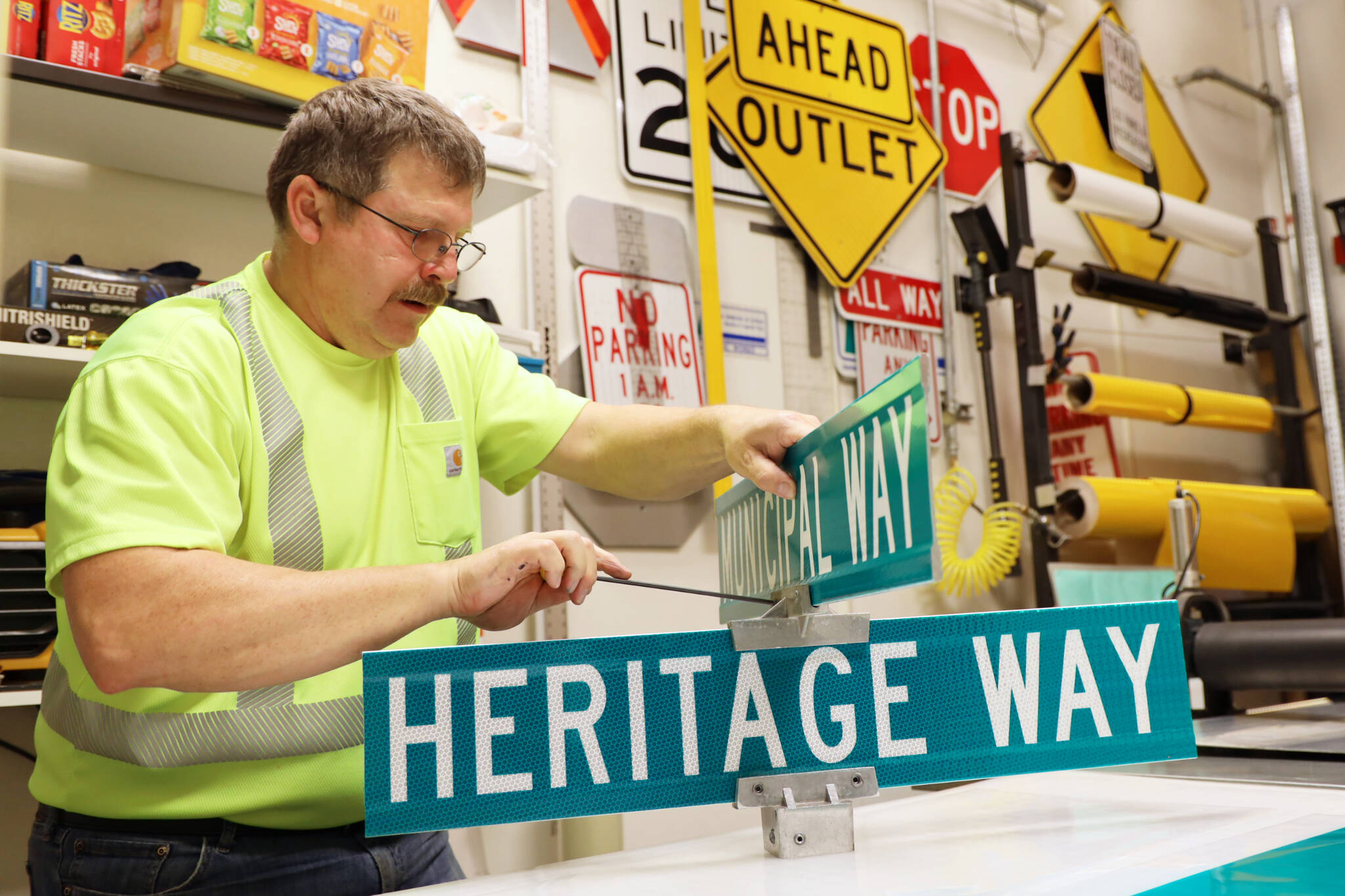 Chris Anderson mounts a Marine View and Heritage Way sign together in preparation for the South Seward Street name change Nov. 1. (Clarise Larson / Juneau Empire)