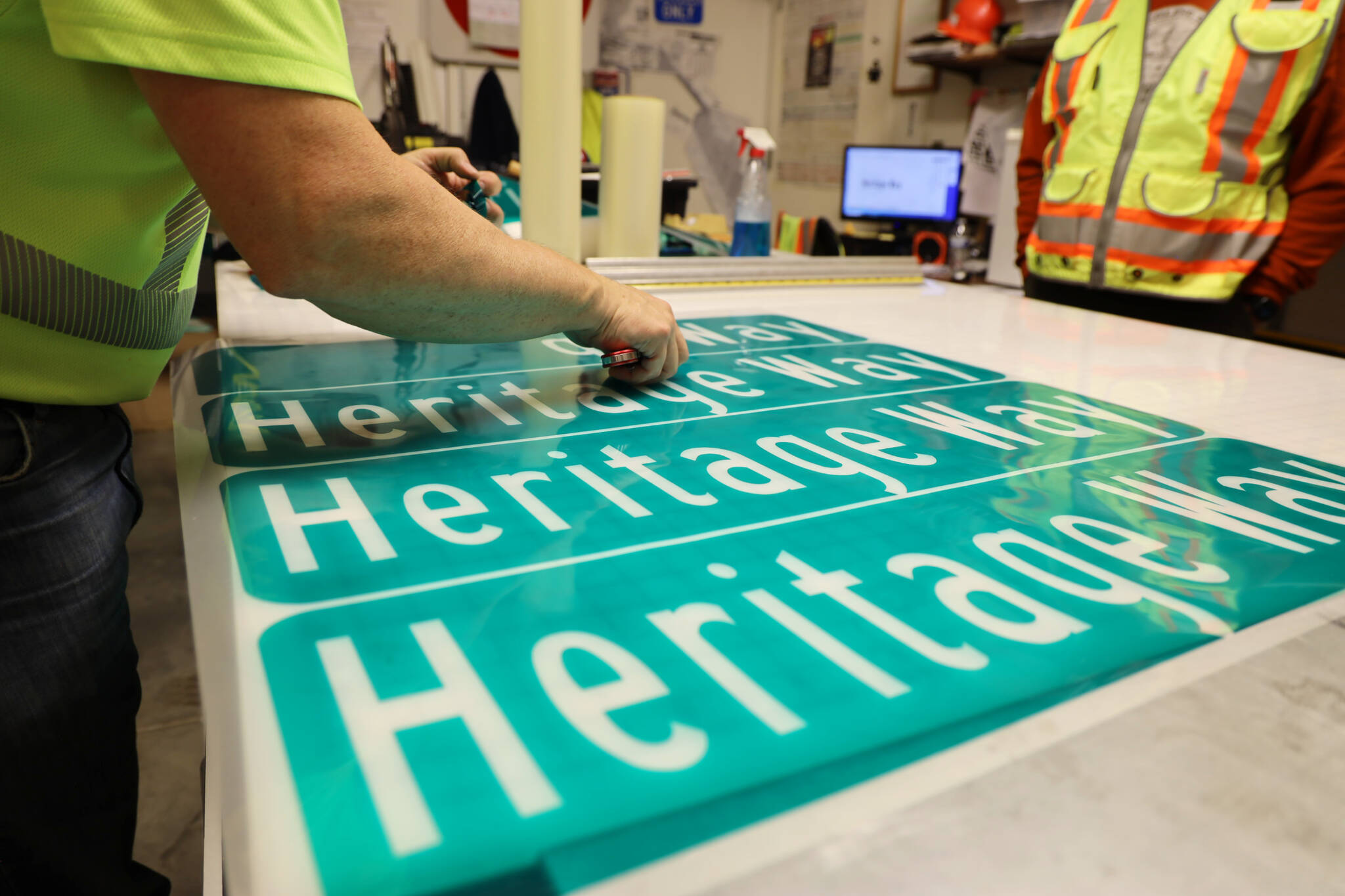 Chris Anderson adds adhesive to the green vinyl that is used to make the new Heritage Way signs ahead of the South Seward Street name change Nov. 1. (Clarise Larson / Juneau Empire)