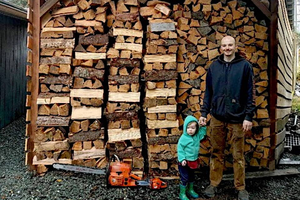 Philip and Ivy White stand next to the “most square/straight/round stack” winner in the first-ever Pioneers of Alaska wood stacking contest. (Photo courtesy of Shannon Crossley/Pioneers of Alaska)