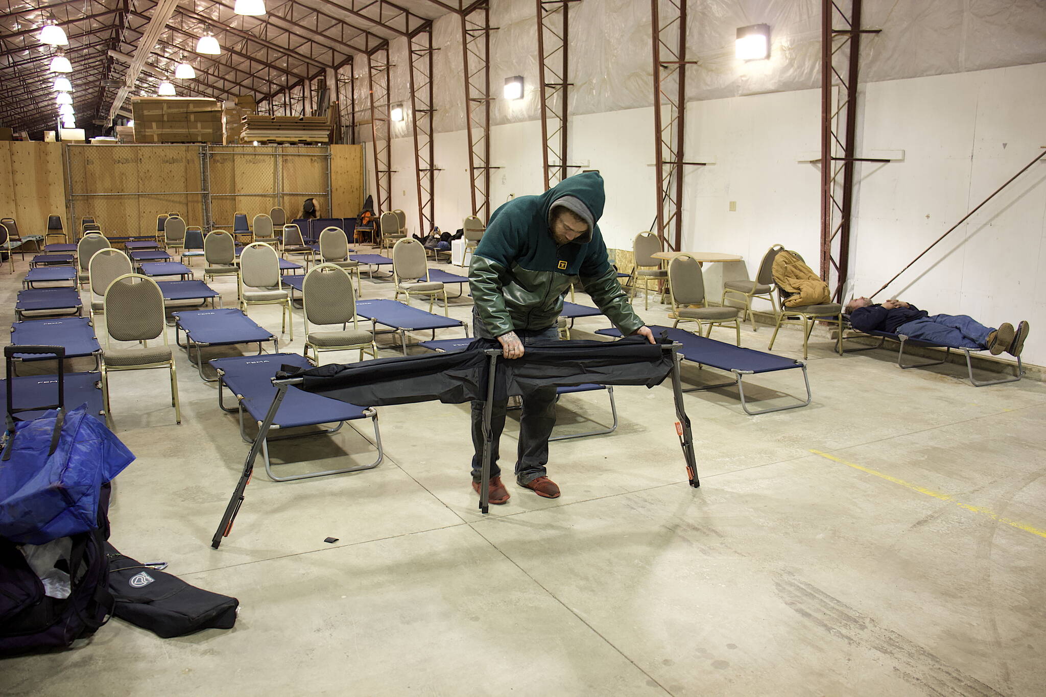 Kevin Jainese sets up his cot along the 40 already provided by staff at the city’s new cold weather emergency shelter at a warehouse in Thane on Friday night, the first for the new facility. (Mark Sabbatini / Juneau Empire)