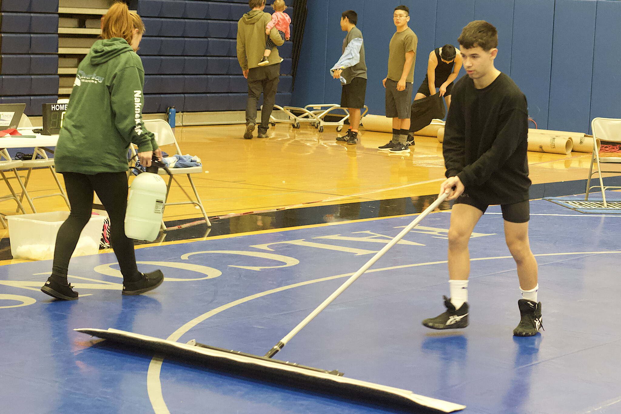 Tristan Ridgeway of Thunder Mountain High School, right, and Lakell Deinhardt of Peterburg High School clean the wrestling mats during a break in the Southeast Showdown at TMHS on Saturday. Ridgeway finished fourth in the 119-pound division of the tournament. (Mark Sabbatini / Juneau Empire)