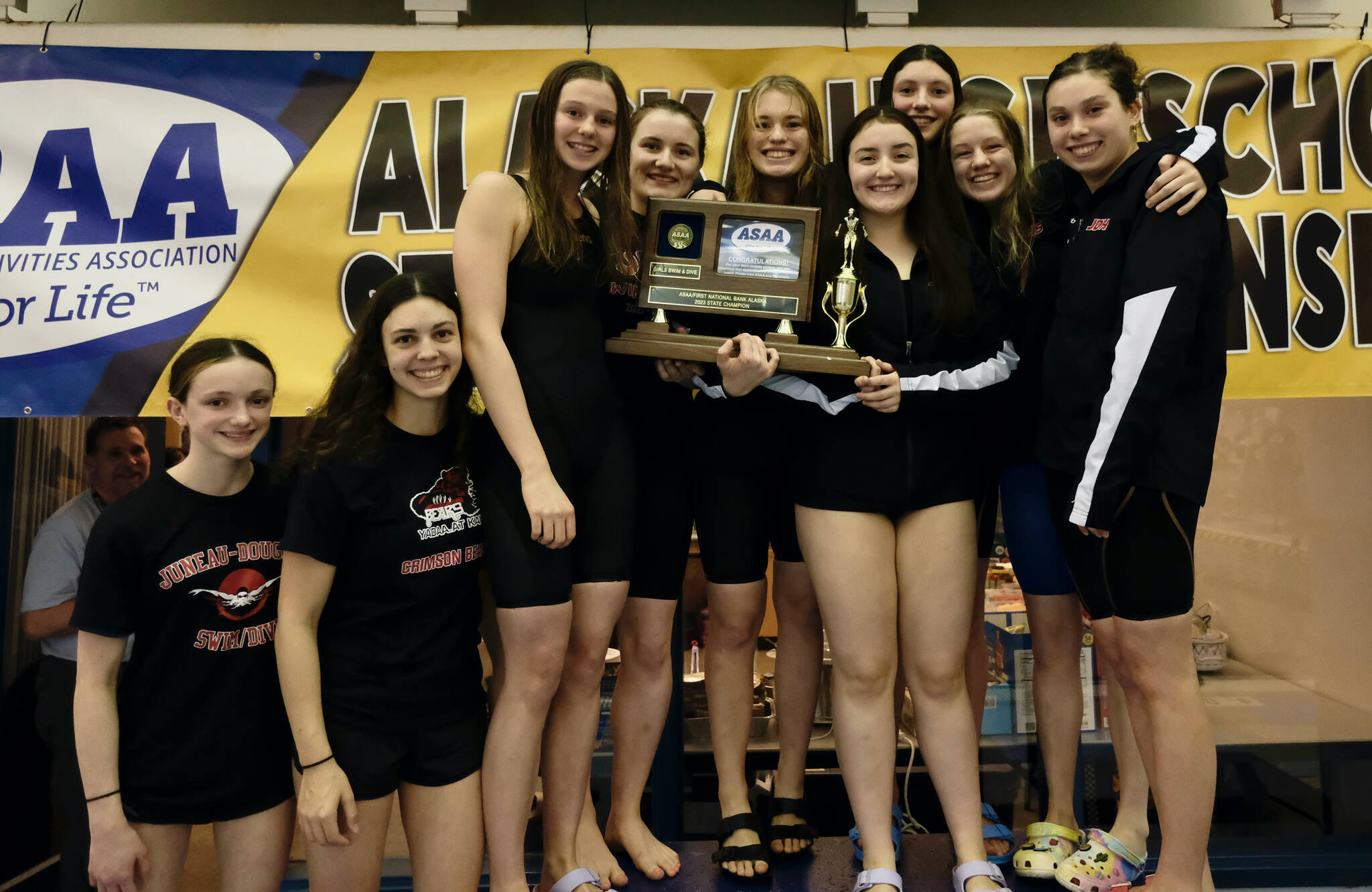 The Juneau-Douglas High School: Yadaa.at Kalé Crimson Bears girls swim team pose on Saturday with their first-place team trophy after the ASAA State Swim & Dive Championships at the Dimond Park Aquatic Center. (Klas Stolpe / For the Juneau Empire)