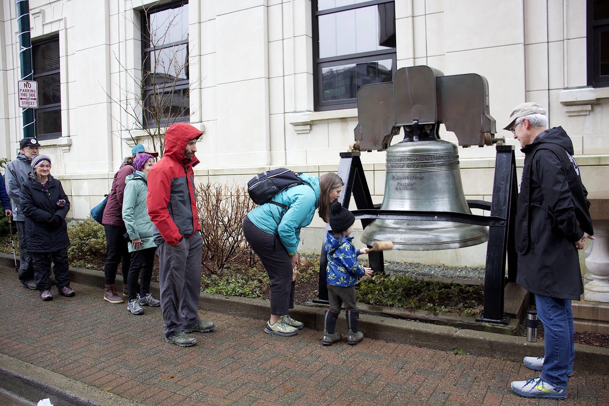 People line up to ring the Liberty Bell replica in front of the Alaska State Capitol at 11 a.m. Saturday during an Armistice Day observation hosted by Juneau Veterans for Peace. (Mark Sabbatini / Juneau Empire)