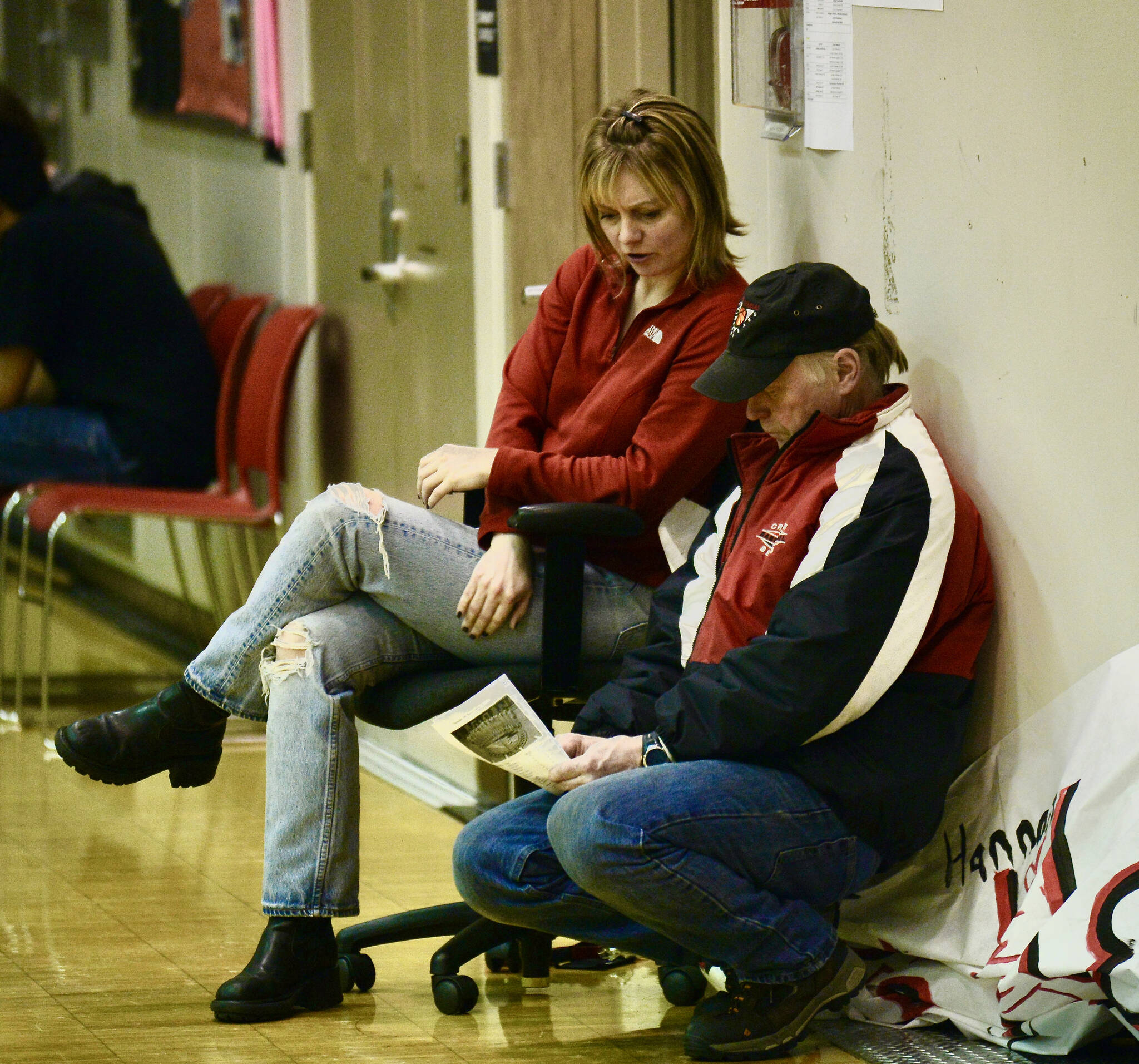 Juneau-Douglas High School teacher Kelly McCormick and George Houston look at a program during a February 2014 game. McCormick was a former student-teacher under Houston. (Klas Stolpe for the Juneau Empire)