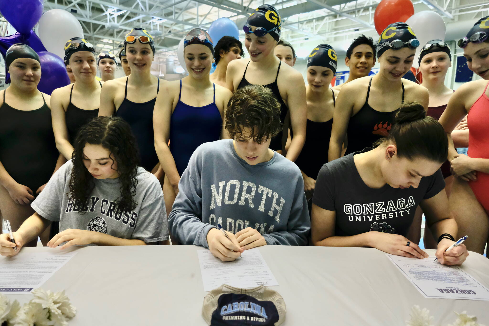 Juneau-Douglas High School: Yadaa.at Kalé senior Samantha Schwarting and Thunder Mountain High School seniors PJ Foy and Olivia Mills (shown with Glacier Swim Club teammates) sign National Letters of Intent (NLI) on Tuesday at the Dimond Park Aquatic Center to swim and study in college. (Klas Stolpe for the Juneau Empire)
