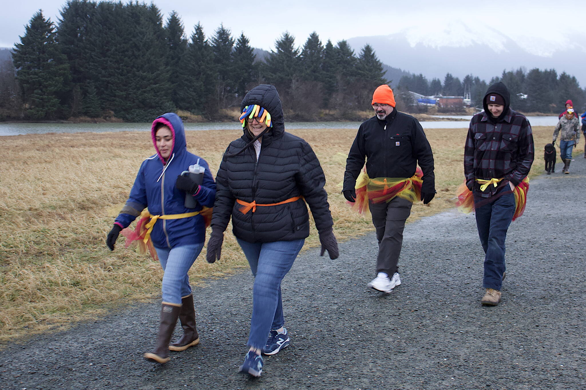 Tristan Baker (center), a Seattle resident who traditionally visits family in Juneau for Thanksgiving, walks with some of them while wearing turkey tutus she provided during the during the annual Turkey Trot 5K and 1 Mile Fun Run along the Airport Dike Trail on Thursday morning. (Mark Sabbatini / Juneau Empire)