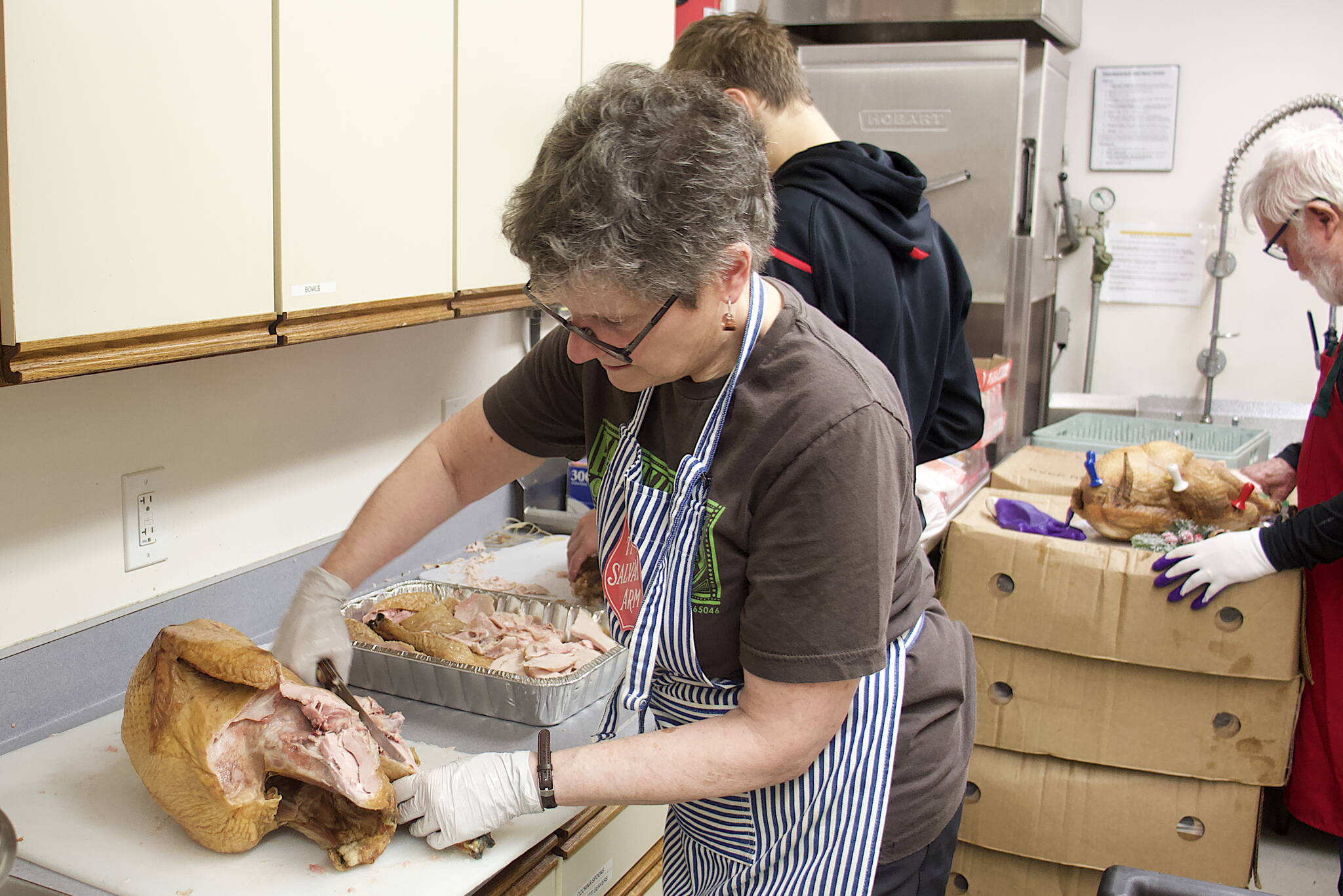 Catherine Johnson carves one of 60 turkeys smoked for The Salvation Army Juneau Corps’ annual communal Thanksgiving meal on Thursday at the Juneau Yacht Club. (Mark Sabbatini / Juneau Empire)